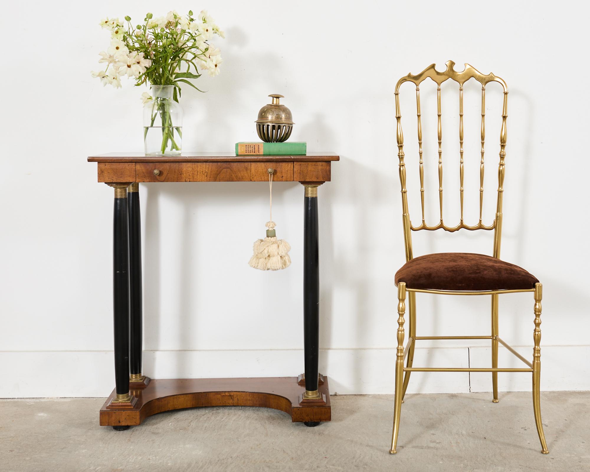Distinctive French late 19th century pier table or console crafted from walnut. The diminutive table features ebonized column legs with patinated bronze mounts in the neoclassical or Napoleonic empire taste. The top of the case is fronted by a