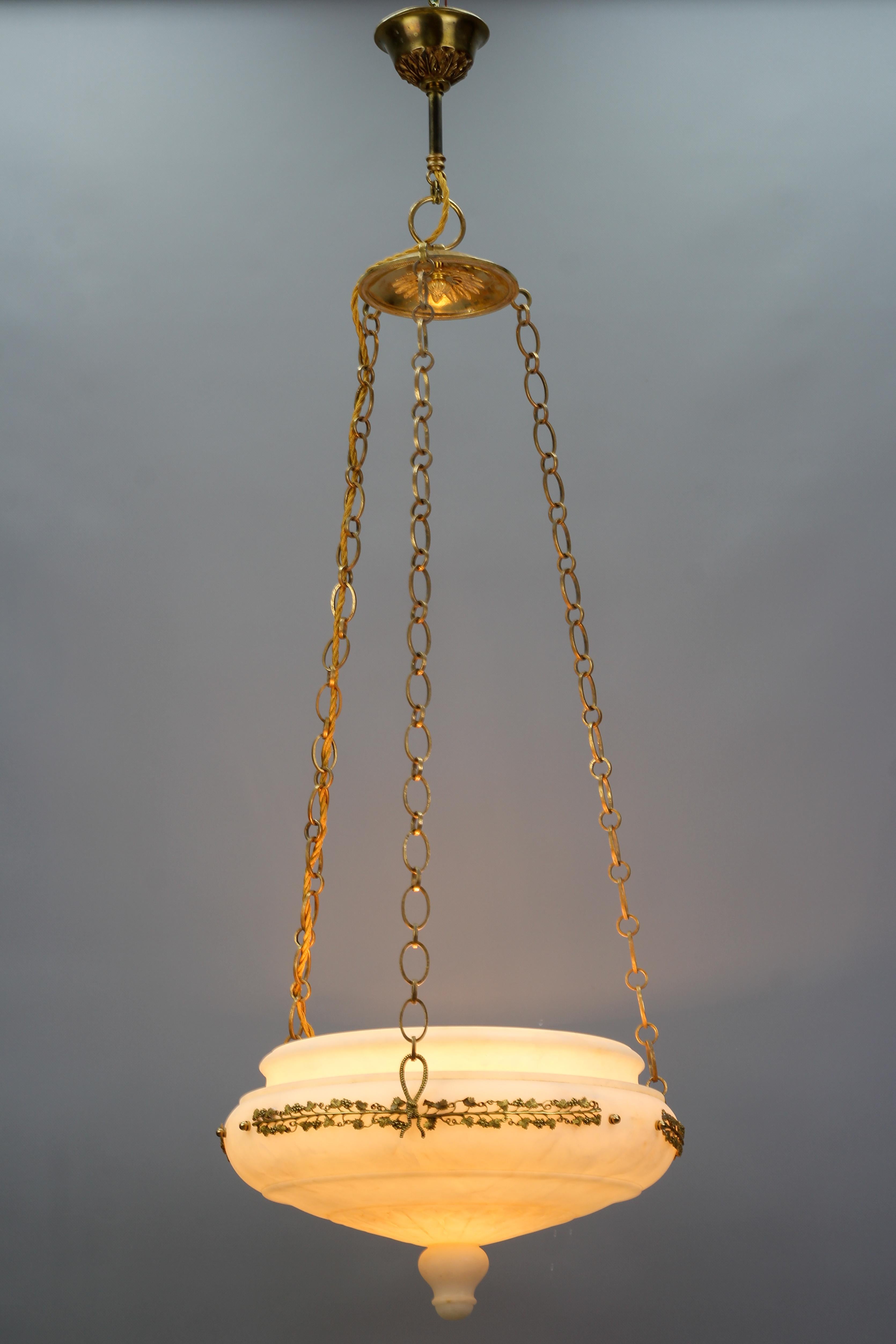French Neoclassical style alabaster, gilt bronze, and brass pendant light fixture.
This impressive antique pendant light features a beautifully shaped carved white and ivory tone alabaster bowl hung on chains and fittings made of brass and gilt
