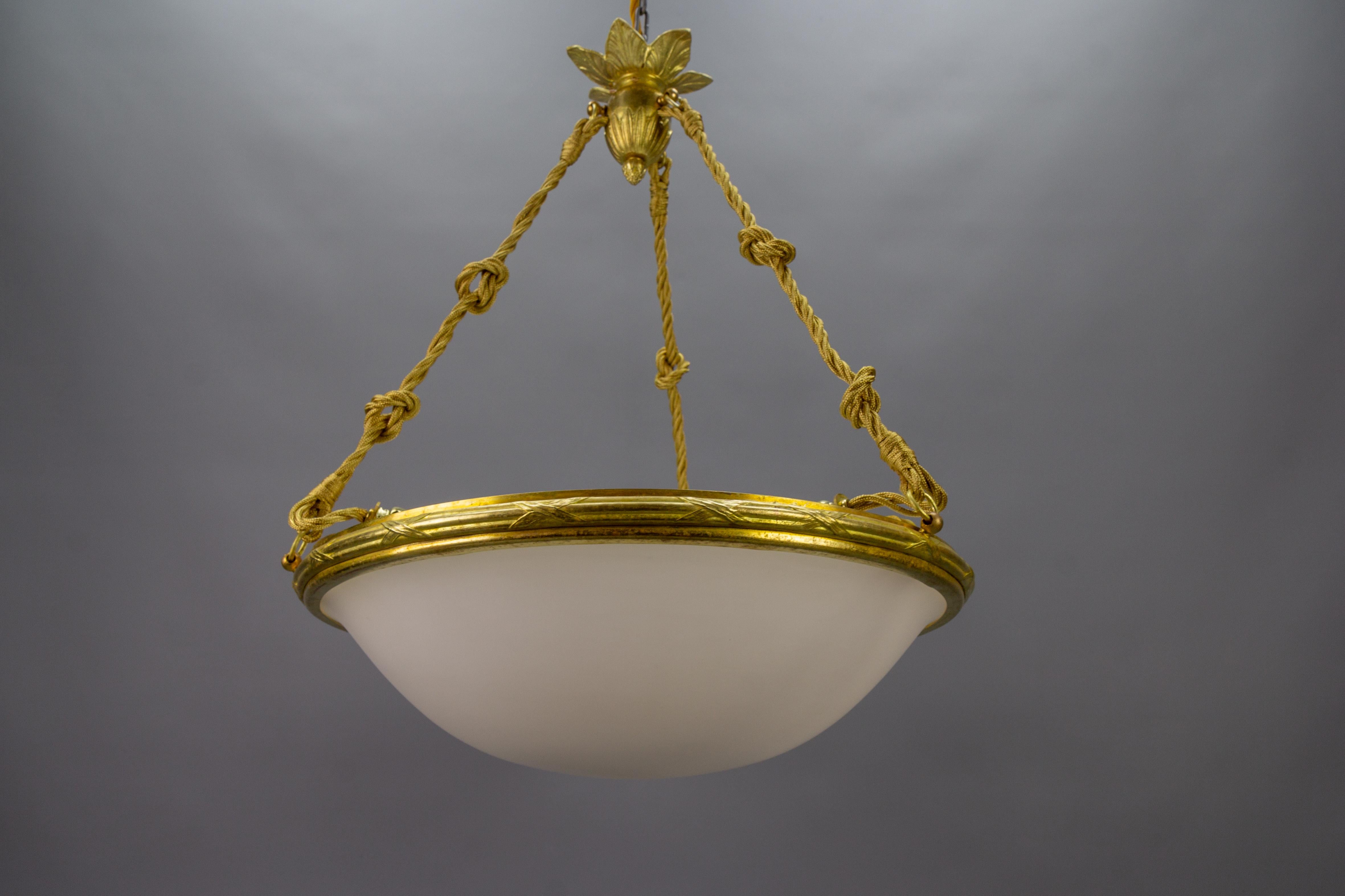 A beautiful Neoclassical style white milk glass pendant ceiling light fixture with an ornate bronze frame. France, 1920s. 
This adorable white milk glass (the inner side of the glass is glossy, outside - matted) lampshade - the bowl is held by a