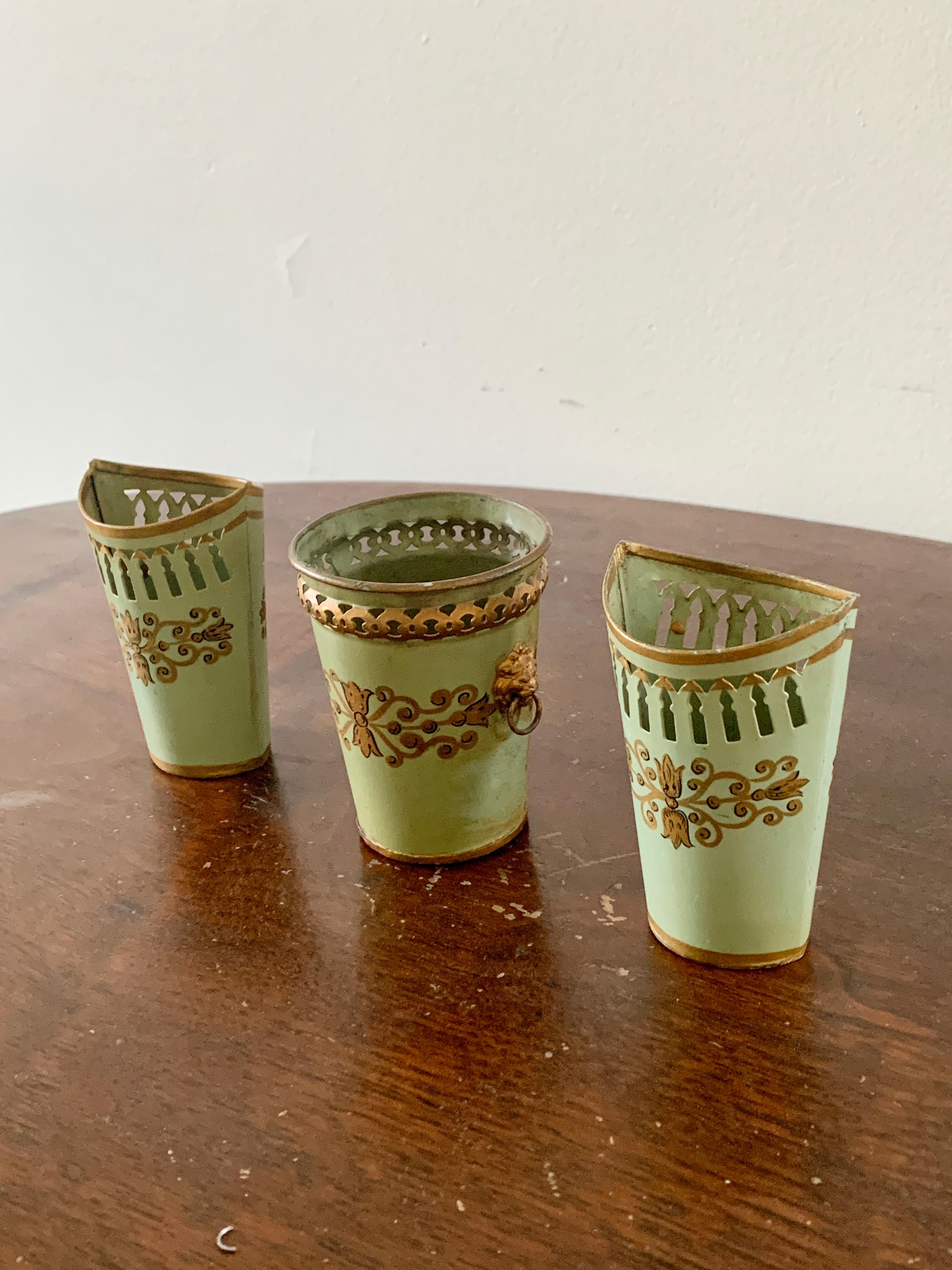 A gorgeous set of three neoclassical green & gold reticulated tole cachepot, planters, or vases. The century vase features brass lion heads. 

France, circa Early 20th century 

Center vase measures: 3