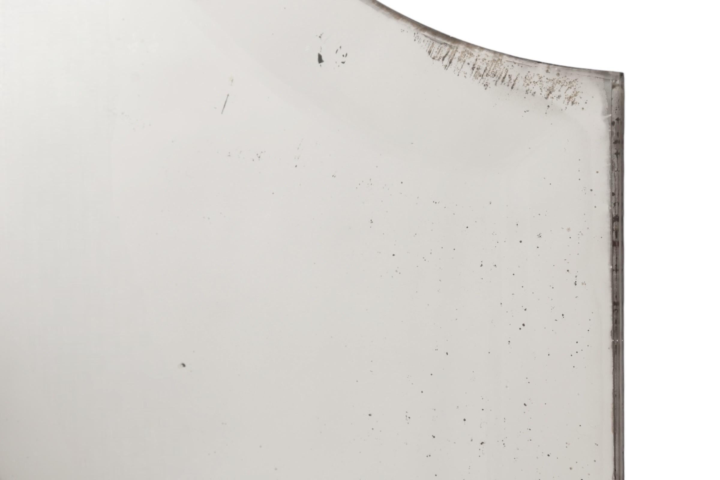 Miroir mural de style néoclassique français datant de la fin des années 1800. Le miroir d'origine présente une légère usure, il est biseauté et son sommet est arqué et non encadré. Les côtés et le cadre inférieur sont décorés de placages de noyer