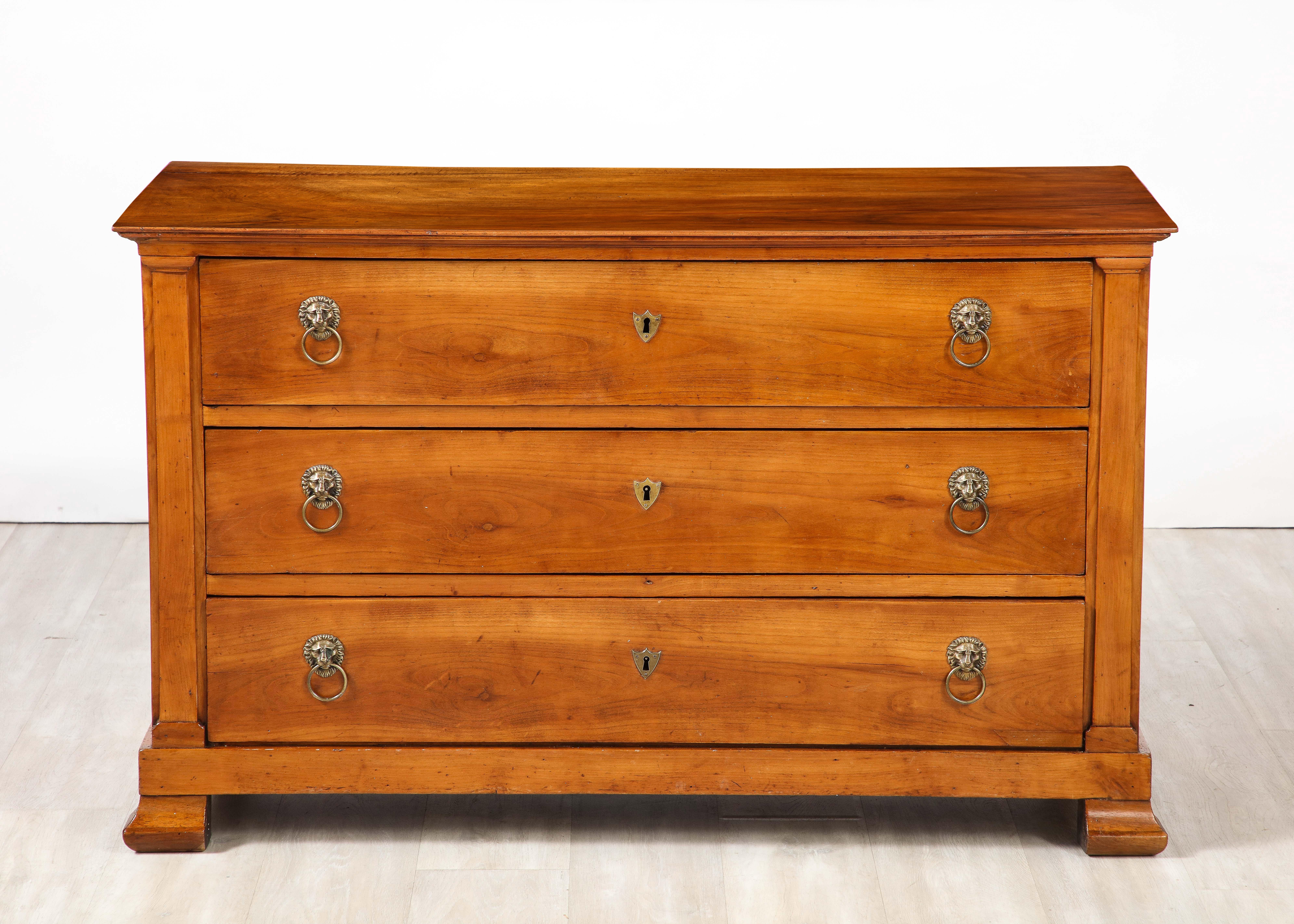 A very fine and handsome French late Neoclassical /early Directoire walnut three drawer commode with elegant brass lion head ring drawer pulls, the whole supported on plinth block feet.  The walnut is rich in color and beautifully contrasts with the
