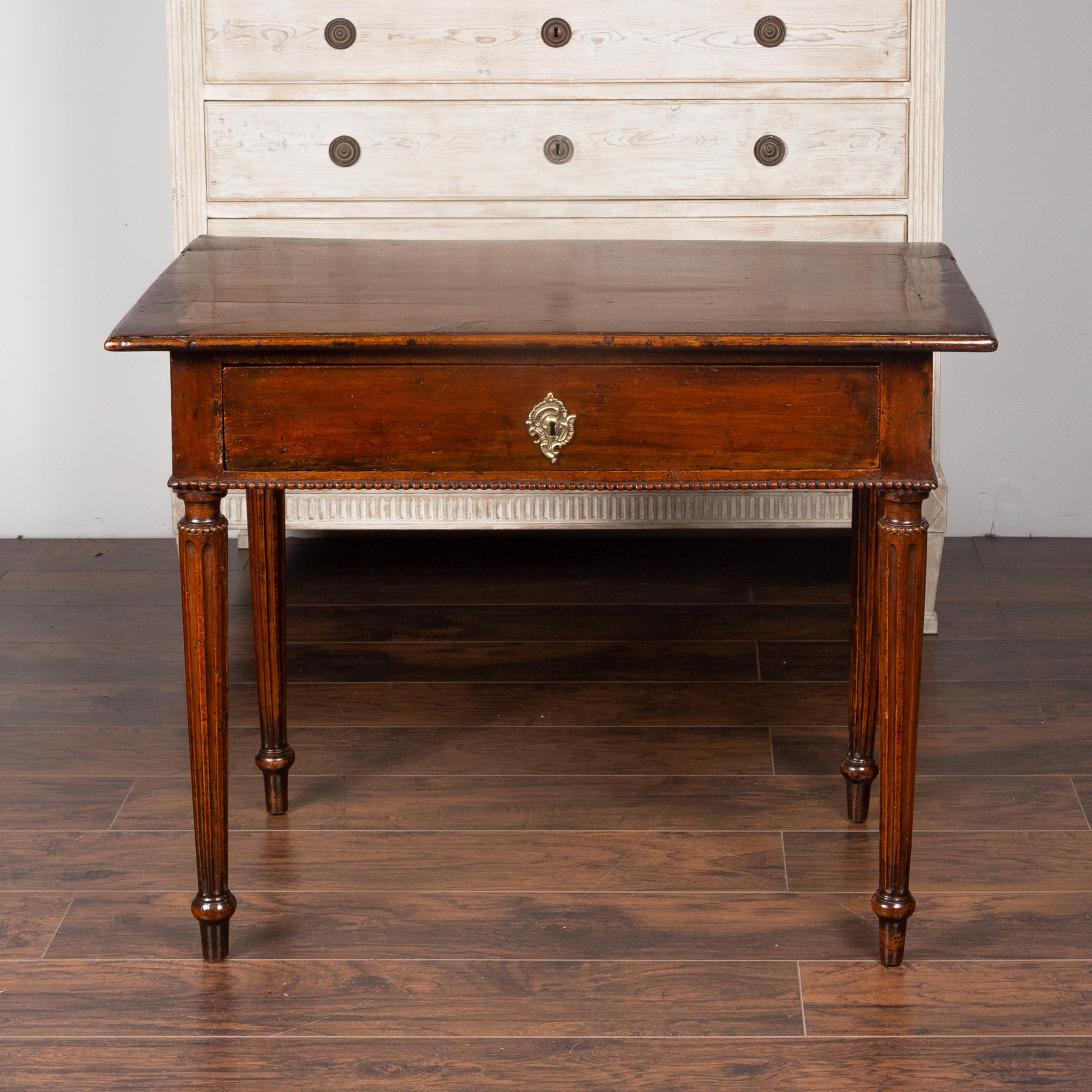 A French neoclassical walnut side table from the early 19th century, with banding, single drawer, beading and fluted legs. Born in France during the early years of the 19th century, this lovely side table features a rectangular top adorned with