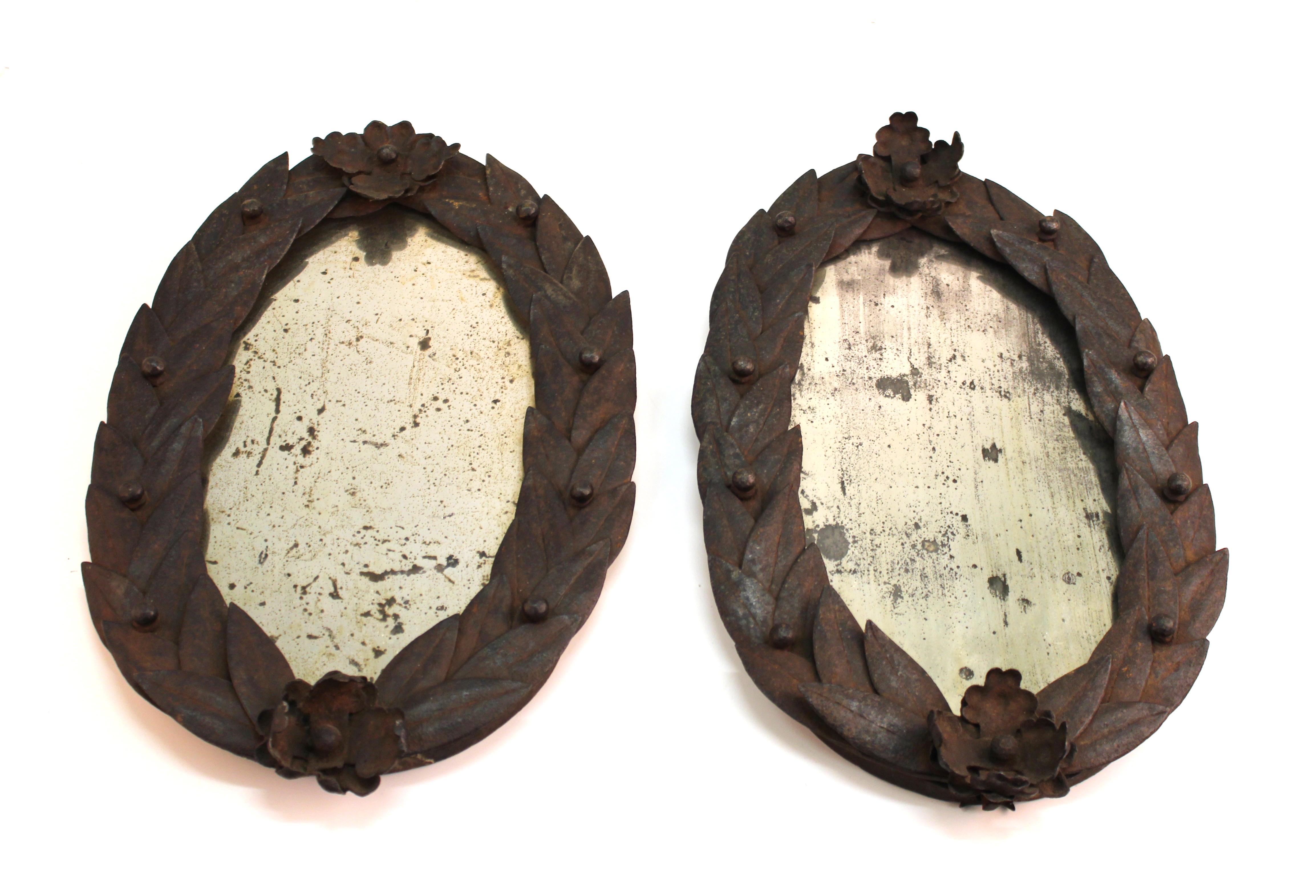 French neoclassical pair of oval mirrors with wrought iron borders in form of laurel leaf crowns. The pair was made in France during the 18th century and is in great antique condition with age-appropriate wear and desirable patina to the iron