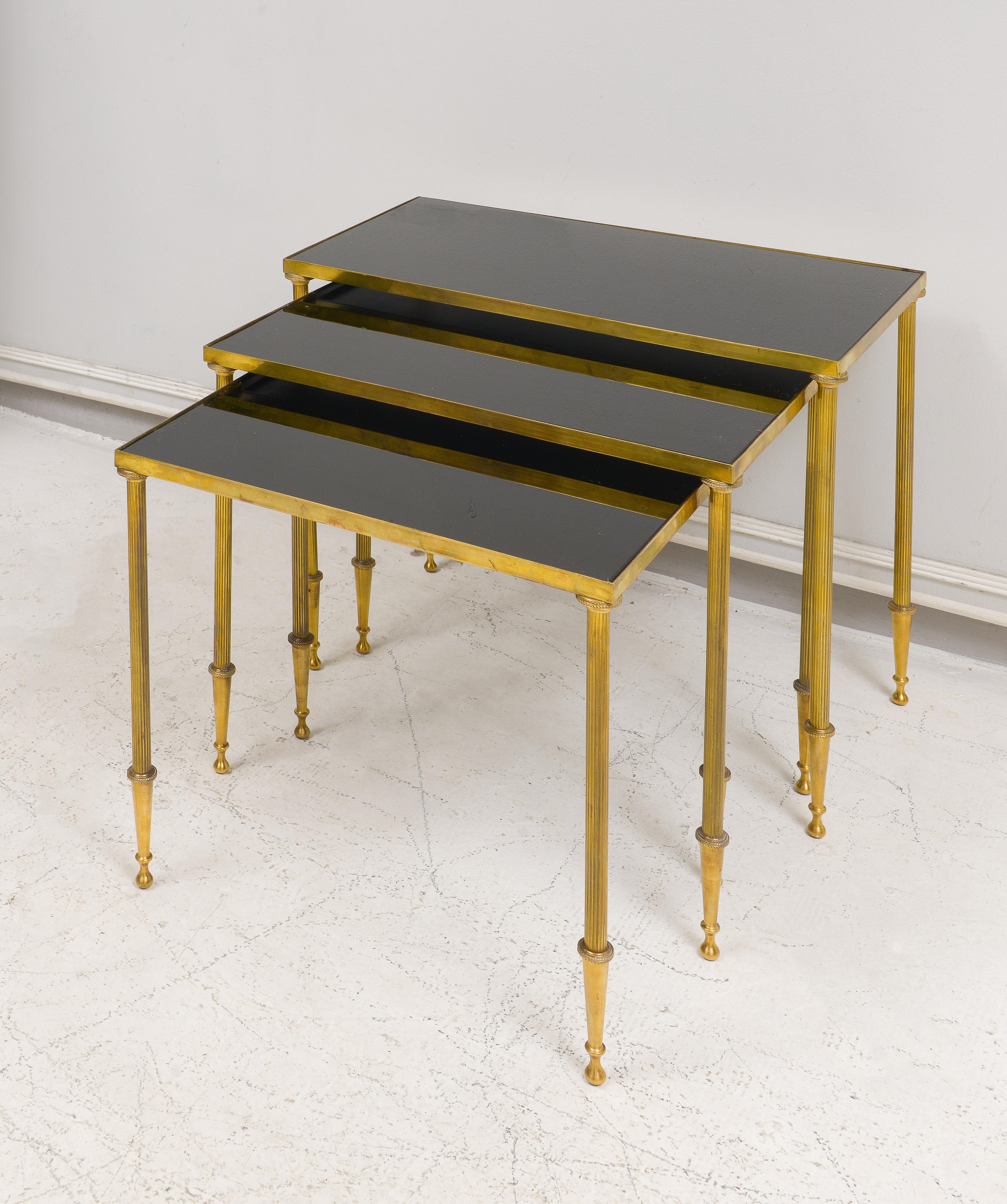Fine Quality French Brass Nesting Tables in the Directoire Manner on Reeded Legs with Black Glass. Set of 3.
Dimensions of each table:
Large:  H 17.25