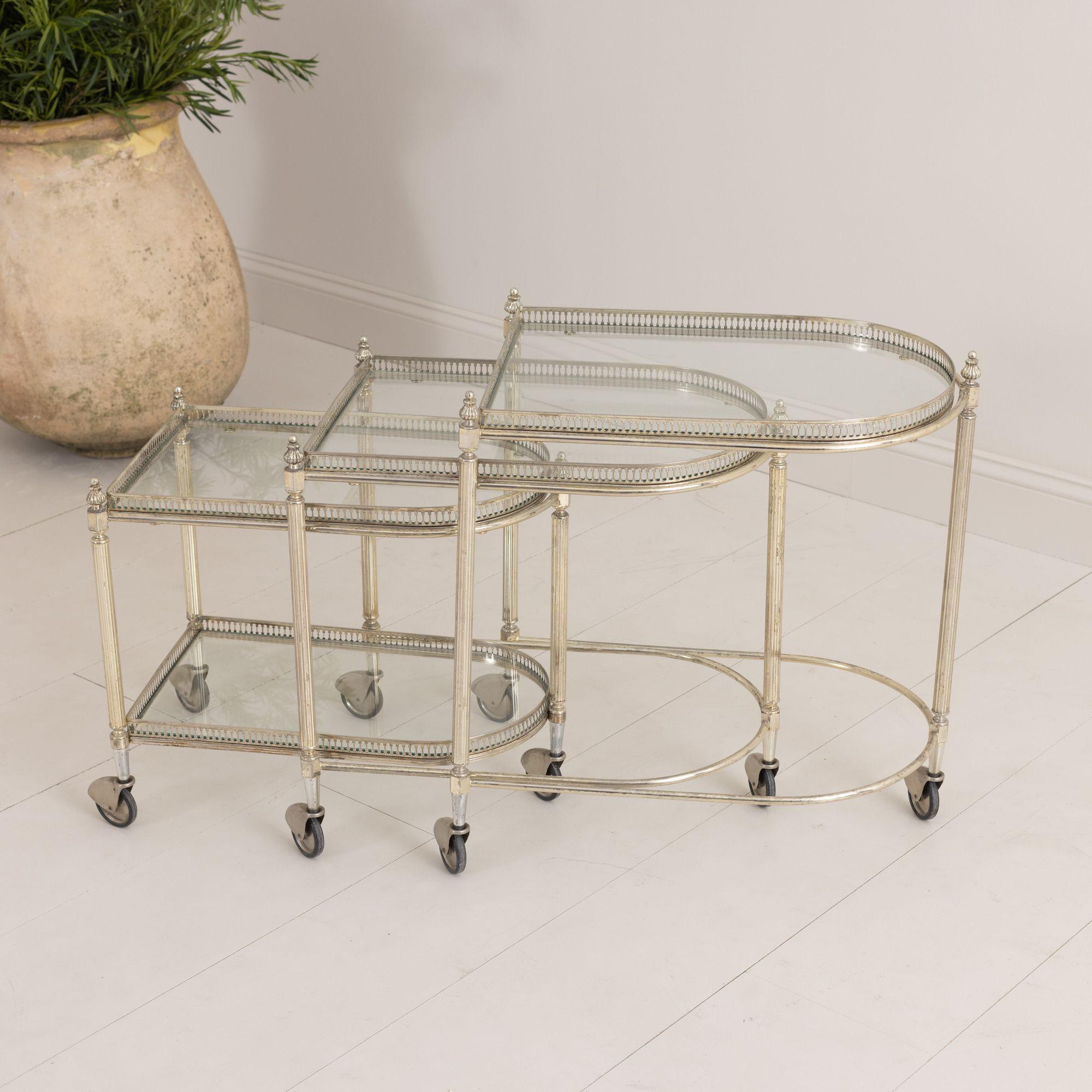 A vintage French nickel serving trolley trio with original castor wheels found in Paris, circa 1940.  Three separate trolley tables with nice elongated shape nest together beautifully. Two-tiered glass with nicely patinated, pierced gallery to the