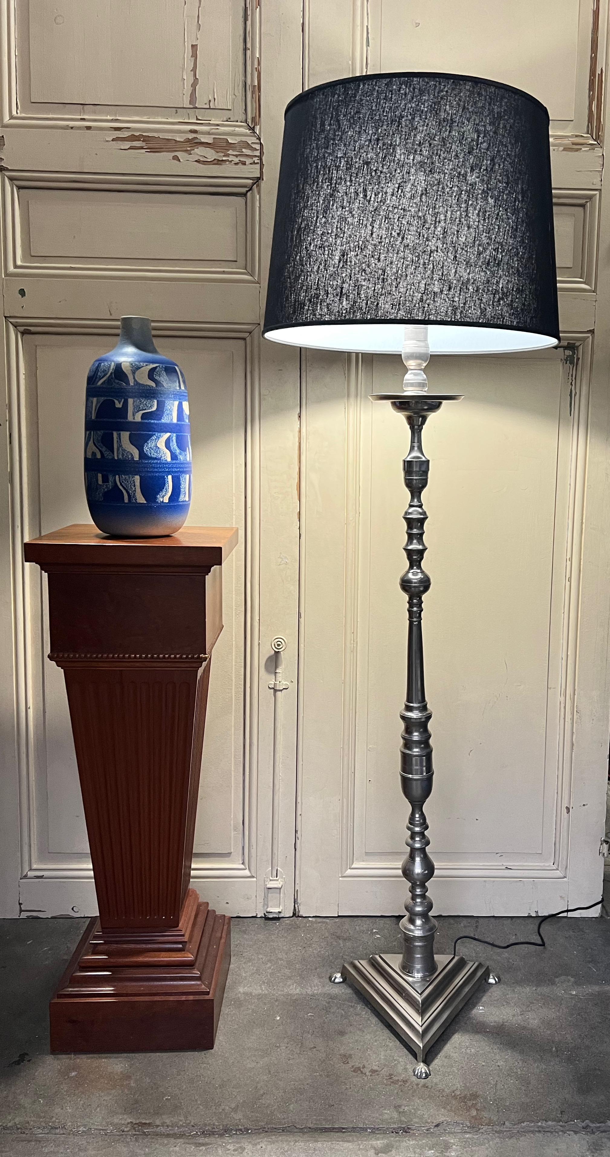 Ce remarquable lampadaire français des années 1940 en laiton et en bronze est monté sur une base triangulaire, dégageant une élégance intemporelle. Récemment plaquée en nickel poli, la lampe présente une surface brillante qui ajoute à son attrait