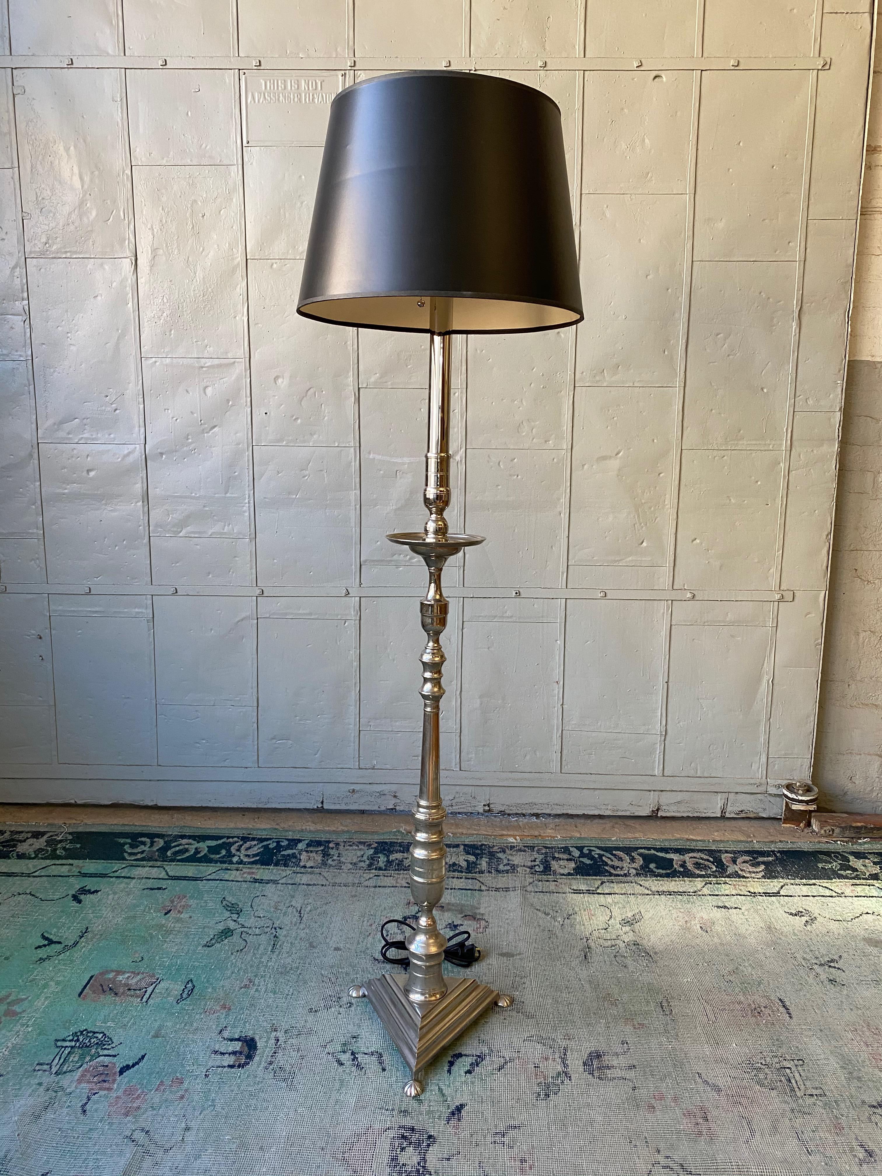 This striking brass and bronze floor lamp stands elegantly on a footed triangular base. Recently plated in a polished nickel finish, the lamp's gleaming surface further enhances its handsome appeal. The floor lamp is wired with a double cluster,