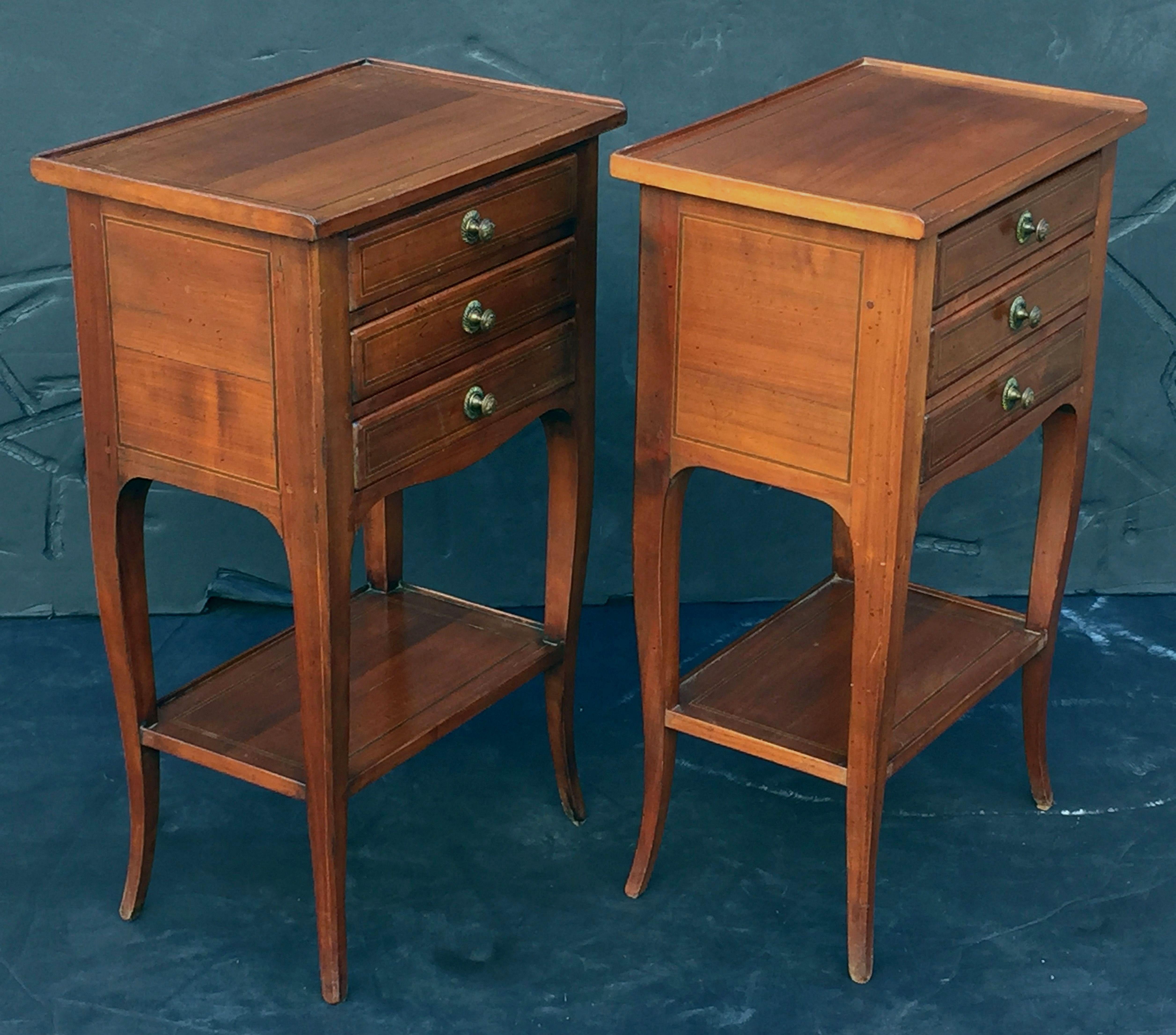 A pair of fine French nightstands or bedside end tables of chestnut - each featuring a rectangular top with gallery over a shaped frieze with three drawers, set upon a turned cabriole leg support with shelf.

Dimensions: H 27 inches x W 16 1/4