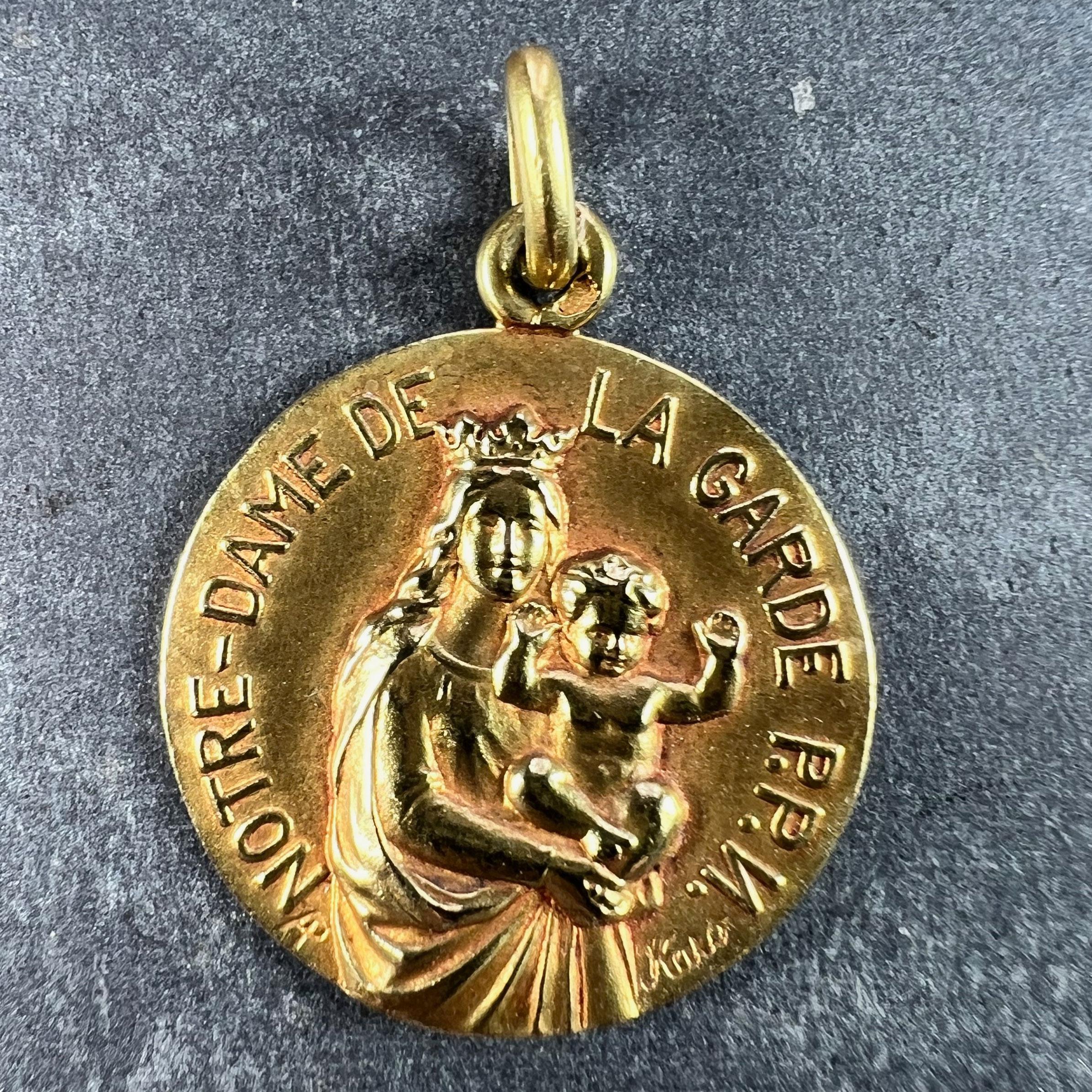 An 18 karat (18K) yellow gold charm pendant designed as a medal depicting the Madonna and Child with the phrase ‘Notre-Dame De La Garde PPN (Preiz Pour Nous)’ (trans. Our Lady of the Basilica of Notre-Dame de la Garde, Pray for Us) around the edge.