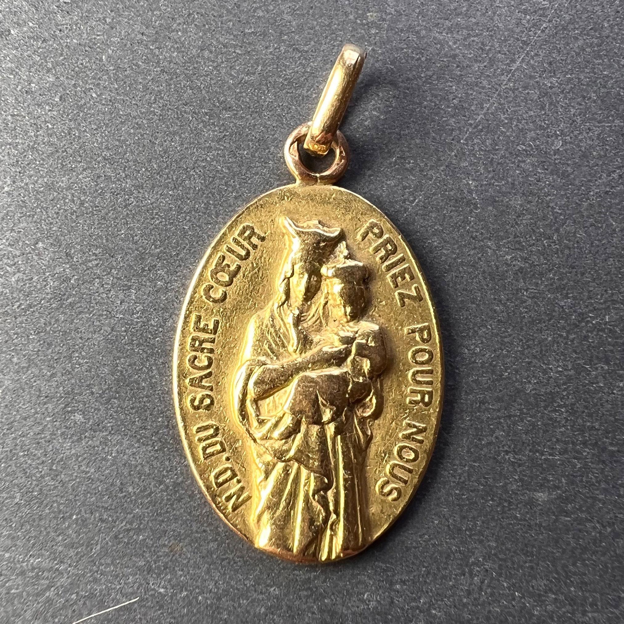 An 18 karat (18K) yellow gold charm pendant designed as an oval depicting the Virgin Mary with the phrase ‘N.D. (Notre Dame) Du Sacre Coeur Priez Pour Nous’ (trans. Our Lady of the Sacred Heart Pray for Us) around the edge. Stamped with the eagle