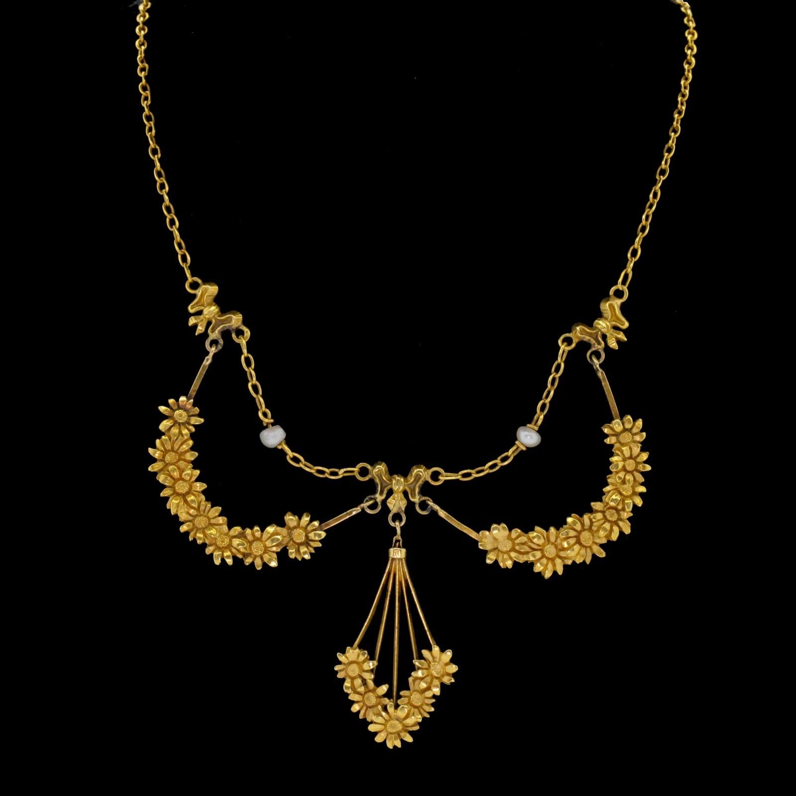 Beautiful coveted French Art Nouveau gold necklace.  This pristine piece is designed with two garlands of daisies and a dangling bouquet that are suspended by ribbons and chain.  The necklace is delicately accented with two round natural Pearls 