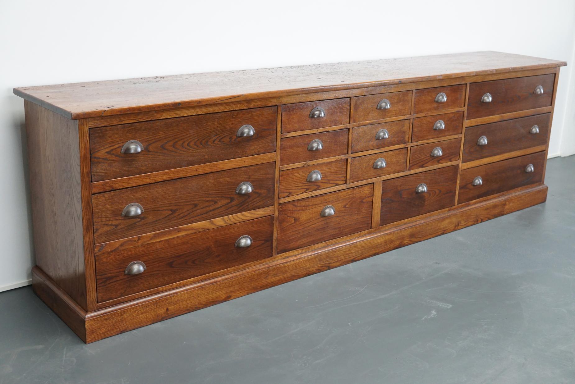 This apothecary cabinet of drawers was designed, circa 1930s in France. The piece is made from oak and features 17 drawers in different sizes with metal handles.