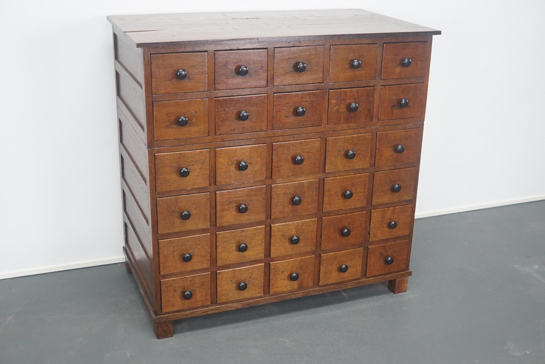 This apothecary cabinet of drawers was designed, circa 1930s in France. The piece is made from oak and features 30 drawers with metal handles round knobs.
 