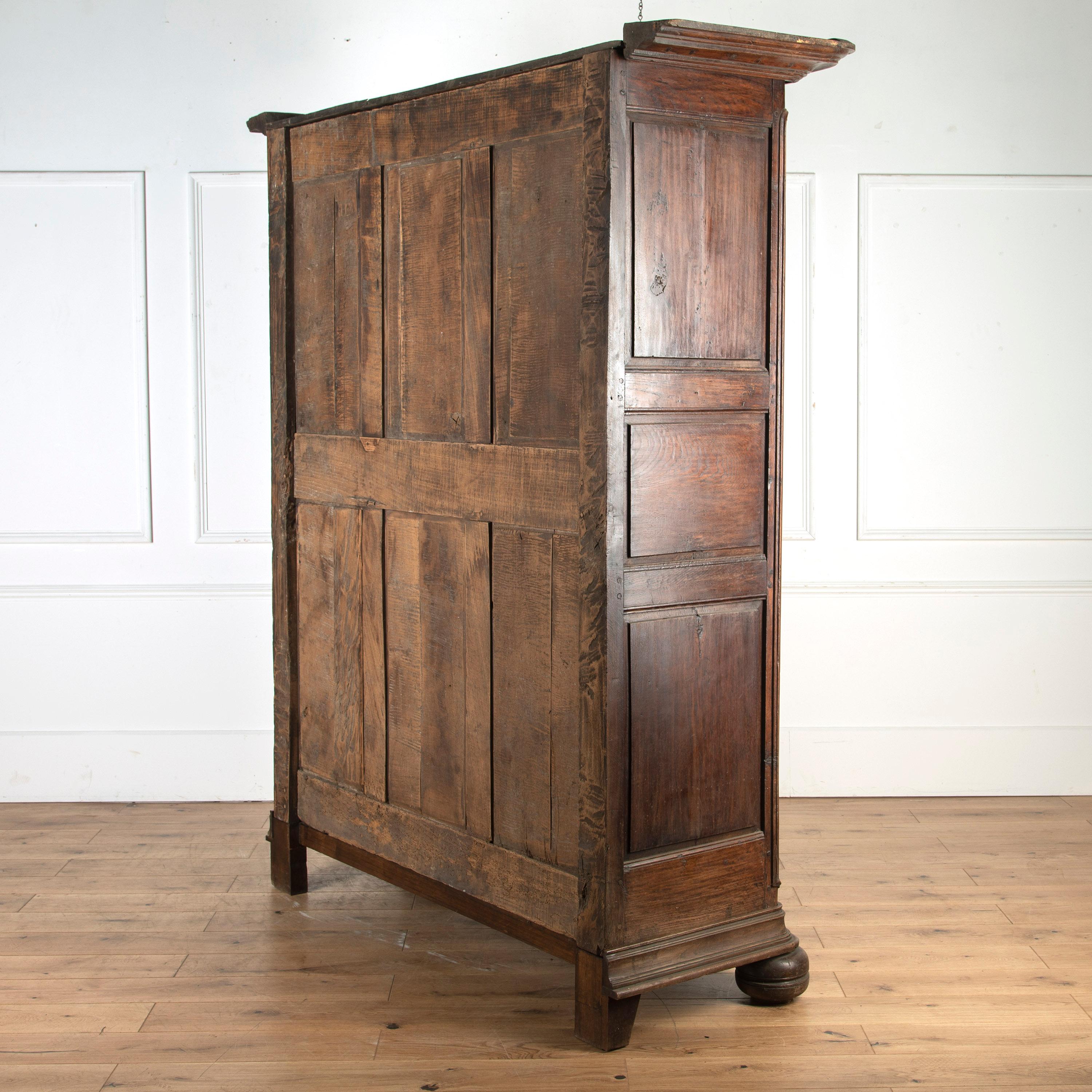 Imposing French oak armoire, circa 1840.

Standing on bun feet with decorative fielded panels and large hinges. The cornice and base plinth is separate from the main body of the wardrobe, making it easier for transportation.

Featuring its
