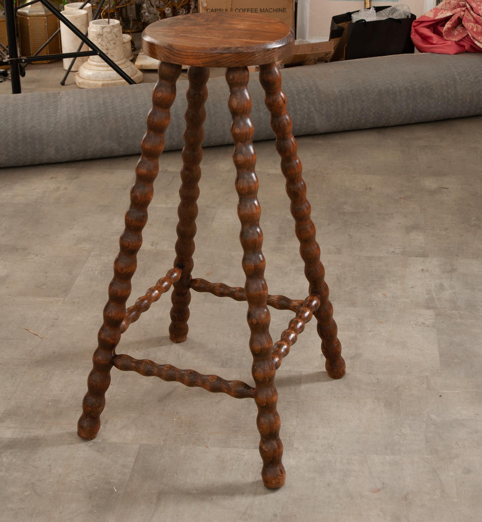 A tall French bar stool or table has playful bobbin oak legs with a stretcher base. Would work well as a plant stand or taller table. Cleaned and polished with a French paste wax, this stool is ready for your immediate use.  Be sure to view all the