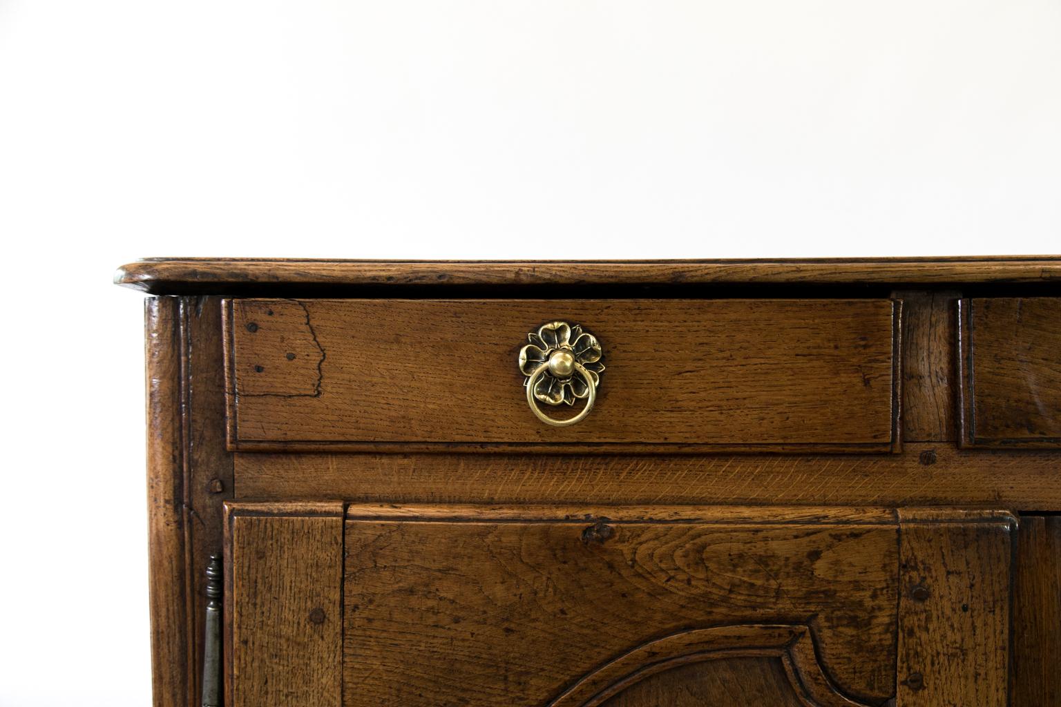 French oak buffet has the original working brass pulls and working lock and key. The top and doors have bullnose shaped molding. The center panels of the doors have a left and right shaped panel framed by moldings. The front and sides have shaped
