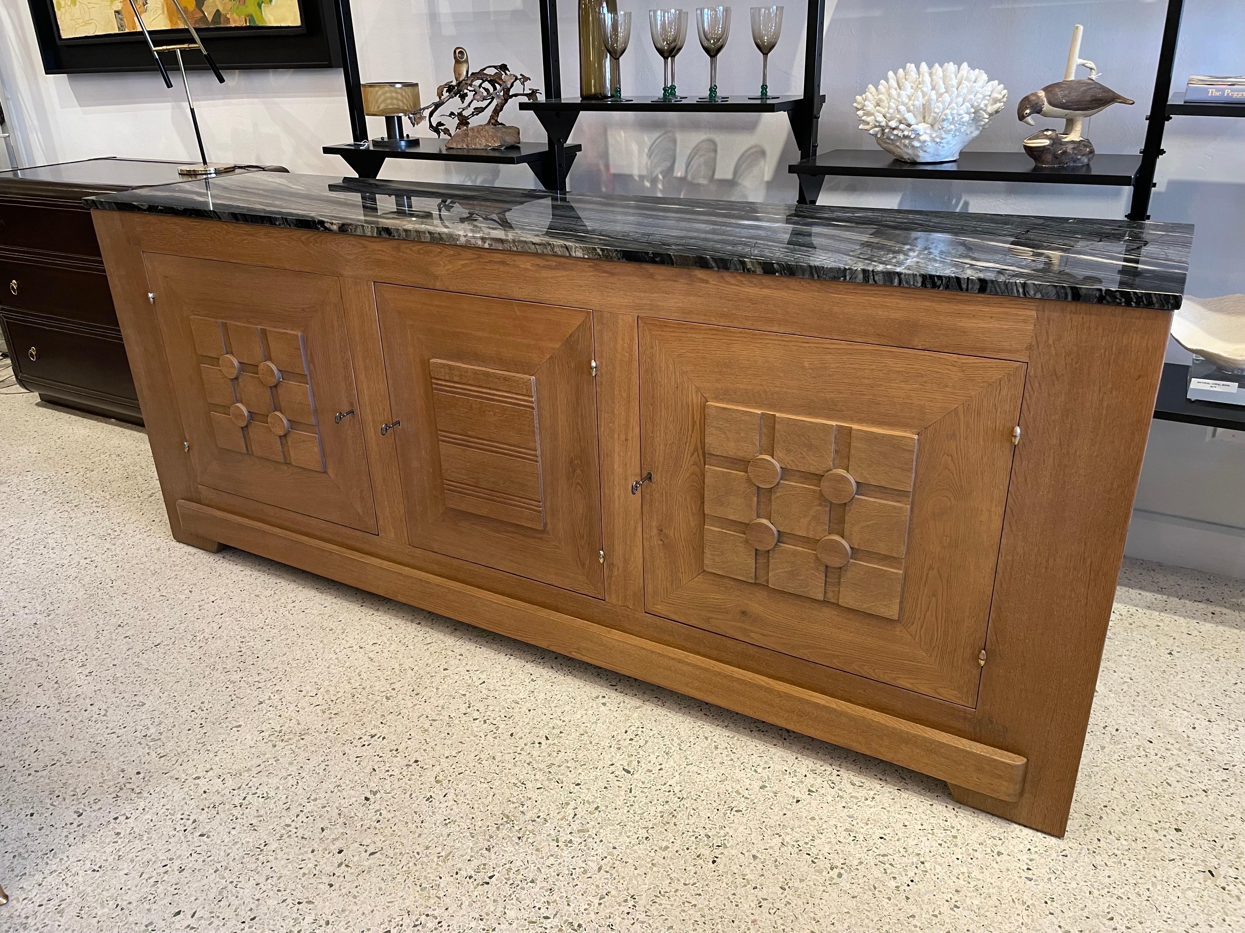 Amazing 3 Door buffet cabinet with carved wood detail ornaments to doors and throughout. Natural French oak with a new Belgian marble to top. Ample shelves and storage, ALL 3 keys work and lock. This is a FIND!.