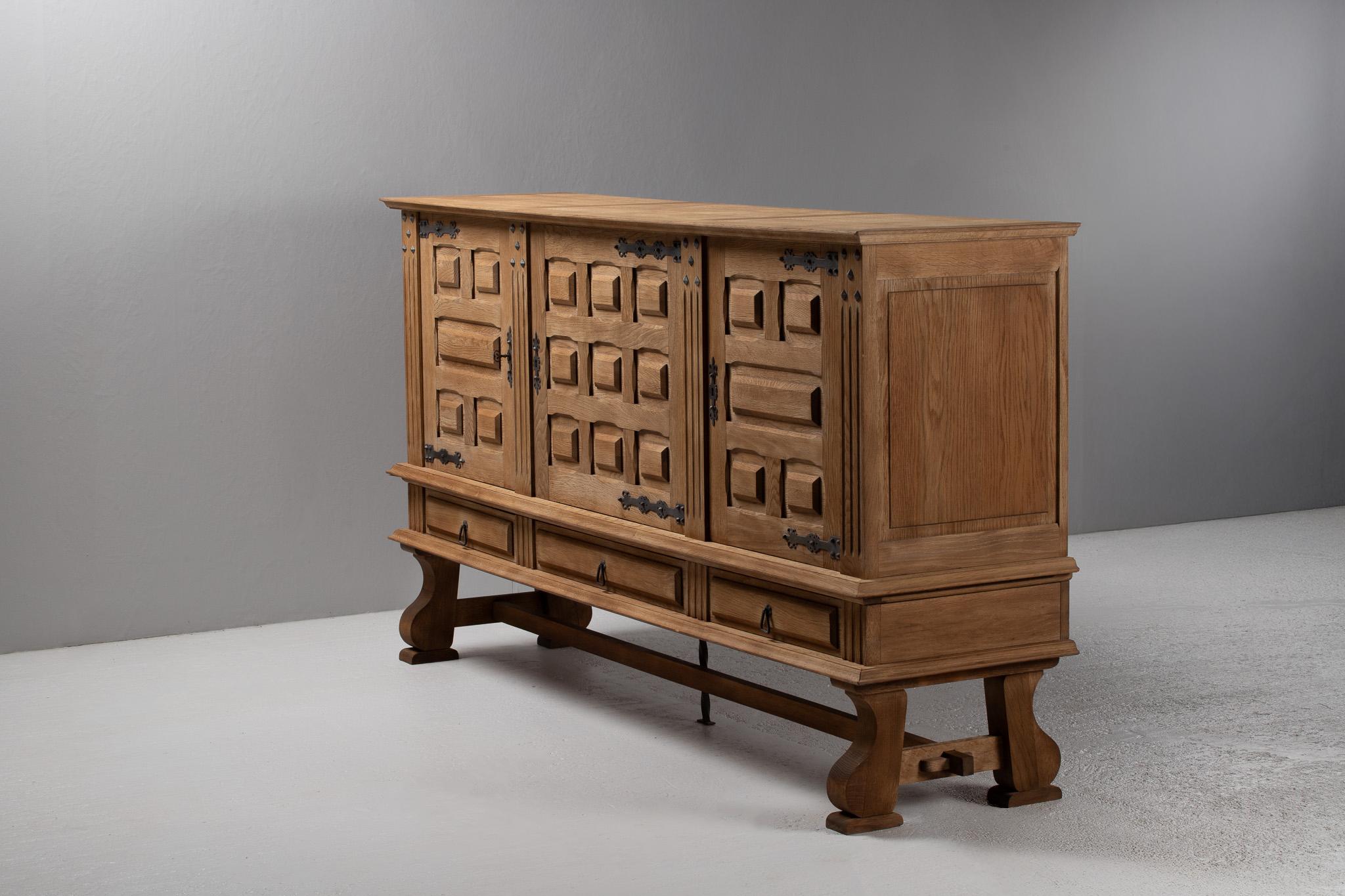 A commanding expression of alpine craftsmanship, this monumental oak buffet marries vernacular strength with sculptural detail. Its façade, composed of deeply recessed geometric panels, evokes a rhythm of light and shadow—each carving a quiet echo