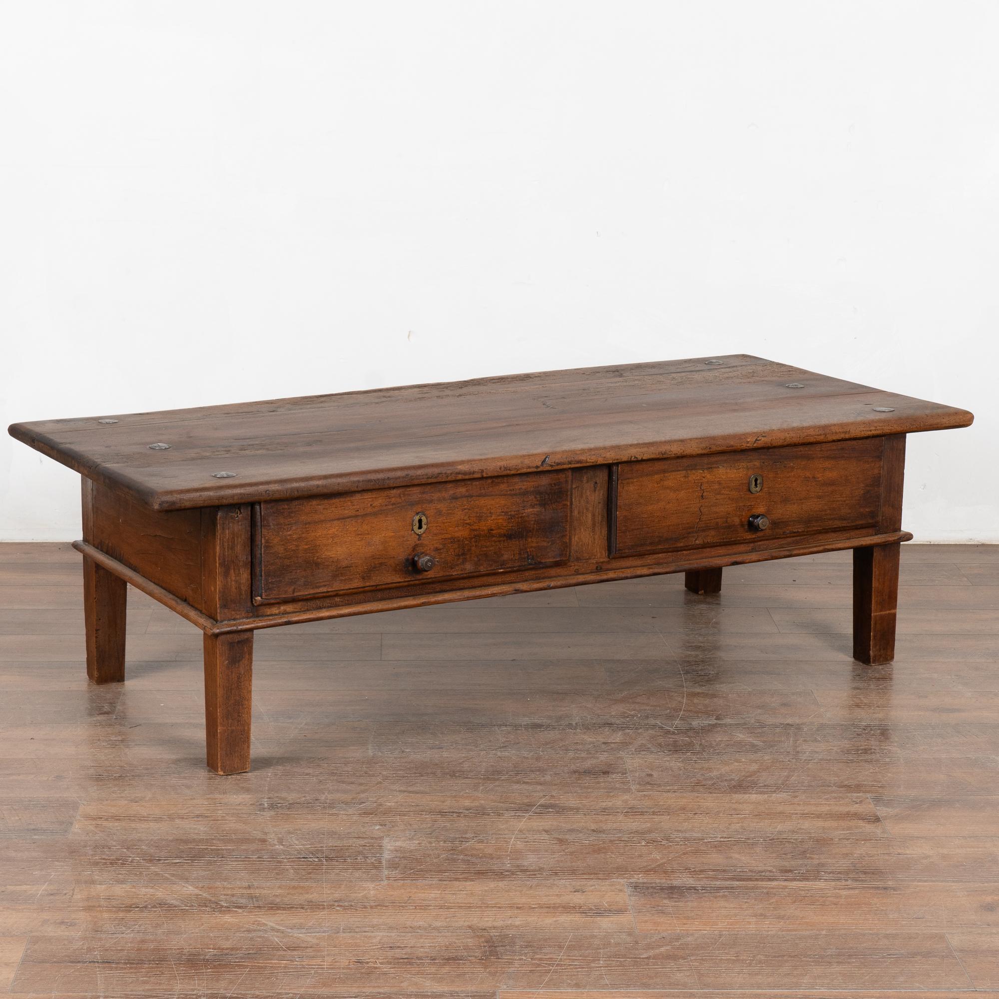 The strong appeal of this coffee table comes from the rich patina of the worn French hardwood. Every scratch, nick, crack and old dried worm holes add to the character of this coffee table.
Two functional drawers with wooden pulls, metal studs in