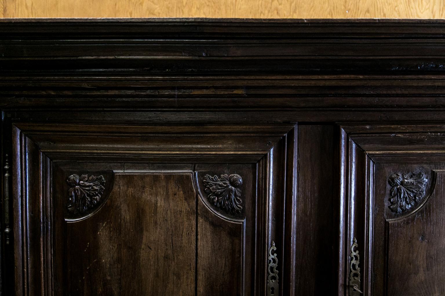 The upper and lower doors of this oak court cupboard have floral motifs carved in high relief. The hinges and escutcheons are original, but the drawer hardware and locks are not. Both drawer sides have three raised panels. There is exposed peg