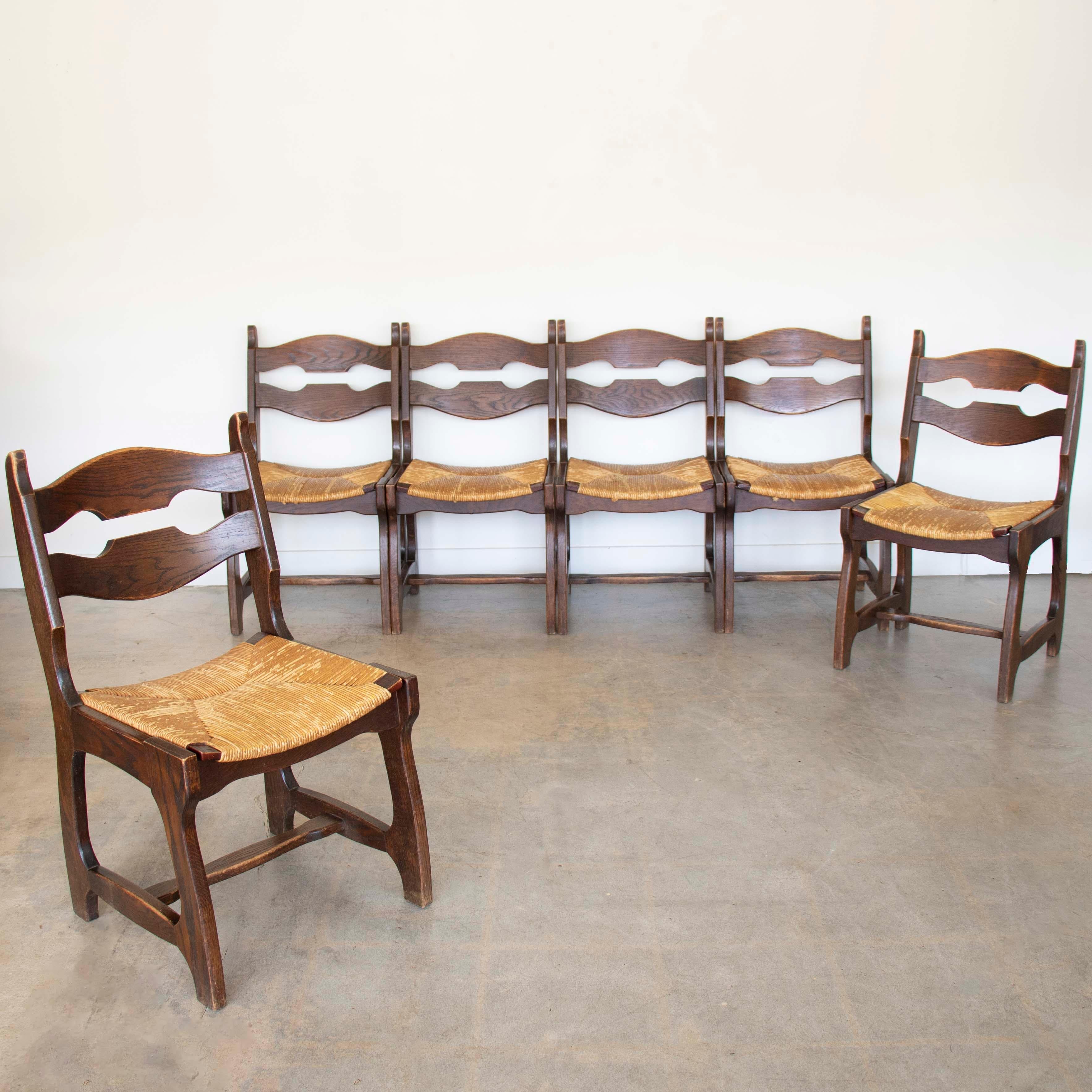 Superbe ensemble de 6 chaises de salle à manger, en chêne massif avec assise en jonc tressé d'origine dans le style de Guillerme & Chambron. Incroyable motif de lame de rasoir découpée au dos. La chaise est en état d'origine et présente des signes