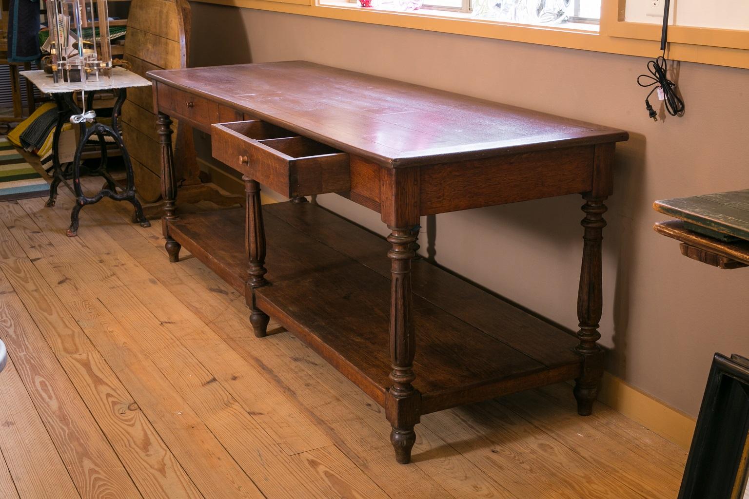 French oak drapery table, circa 1880-1900. Long drapery table, with two front drawers and under-shelf, supported by six turned legs. Very good condition with some period repairs to top. Can function as an island, library table, sofa table, console