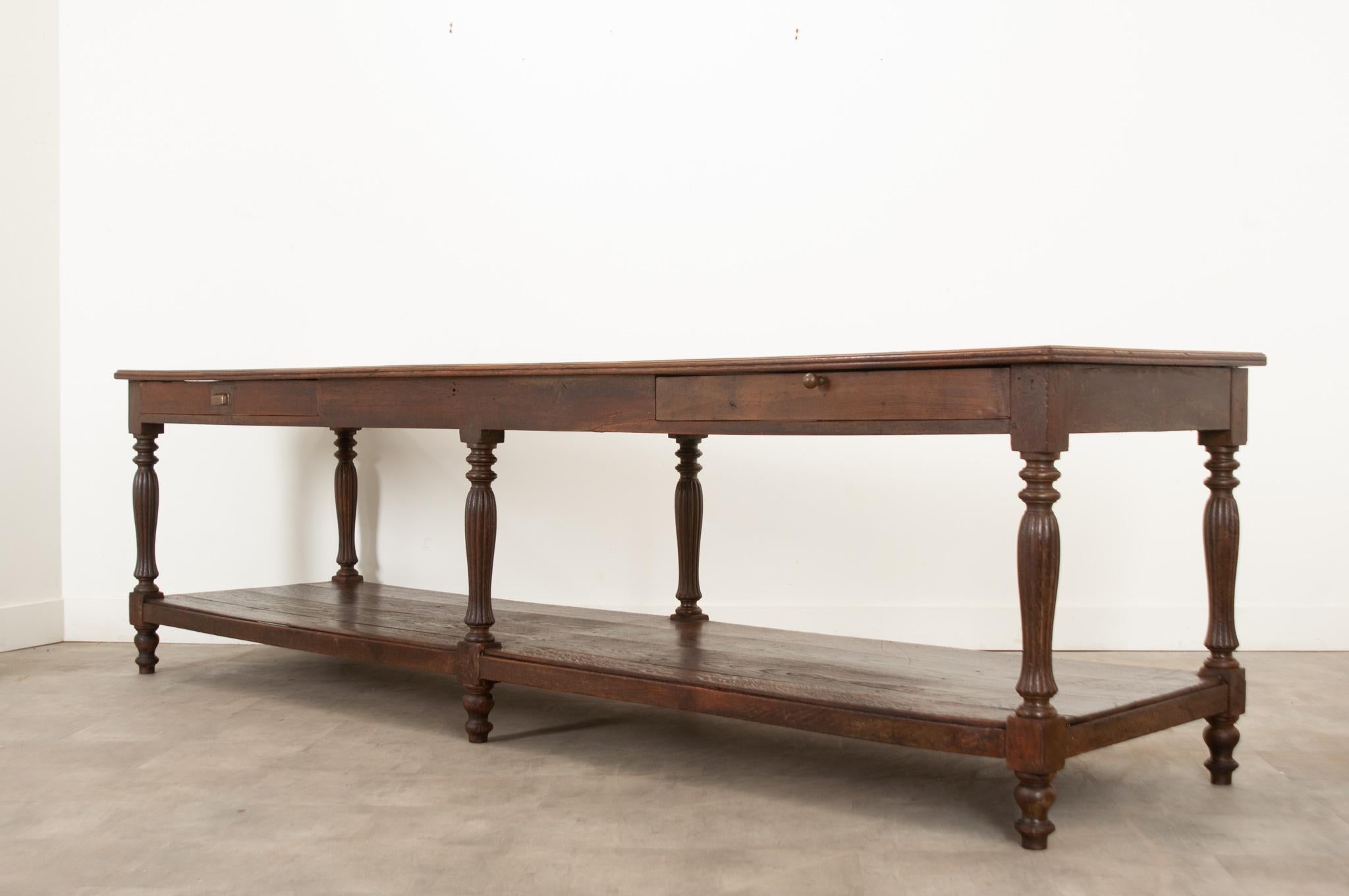 This grand French oak drapery table is over 10 feet long.  The top surface is constructed of parqueted hardwood and has obtained a beautiful patina over the years.  There are two drawers with handles on one long side of the table that slide with