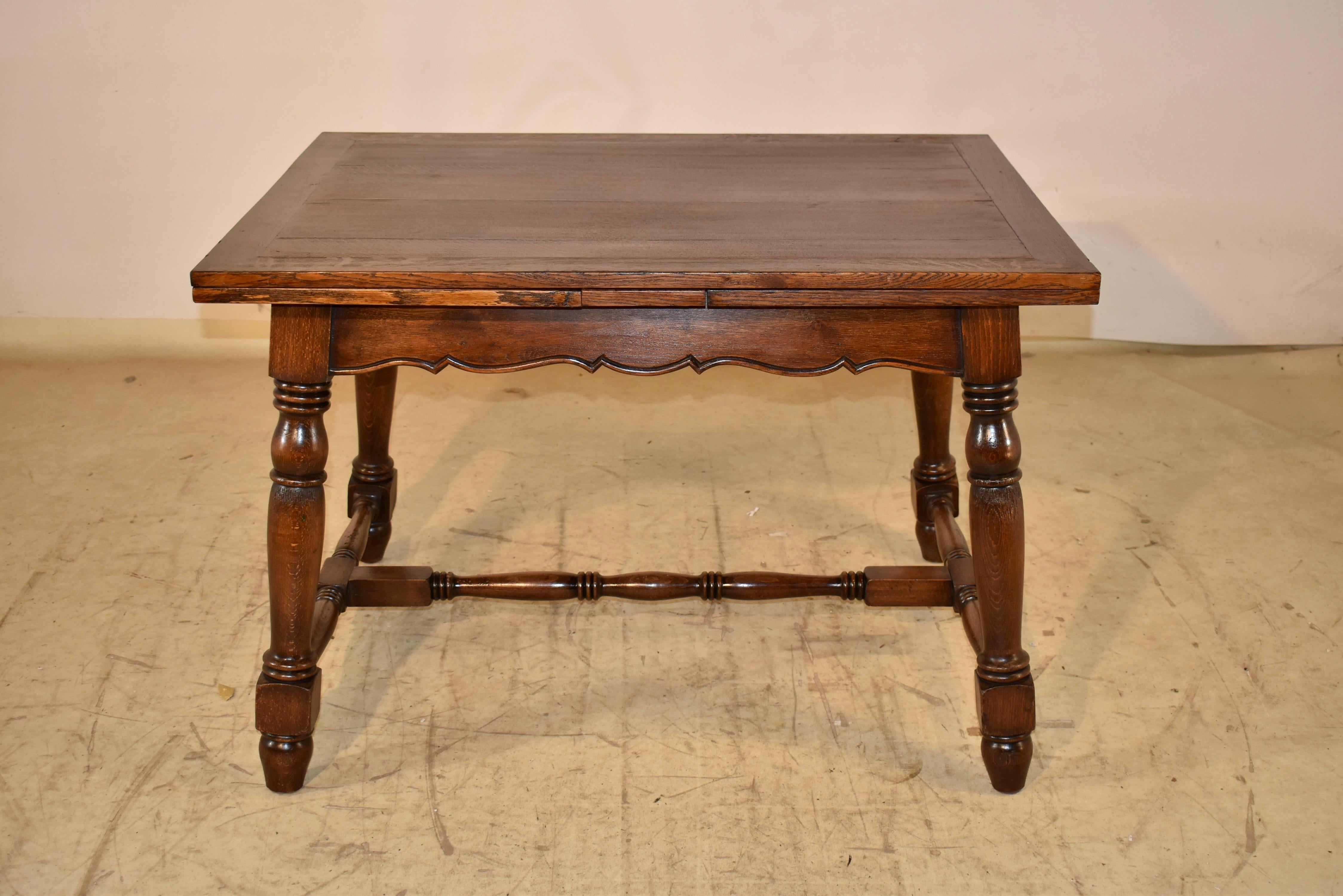 Circa 1900 oak table with two draw-leaves from France.  The top and leaves are banded and follow down to a simple and scalloped apron.  The top measures 80.25 inches in length when the leaves are extended, and the apron measures 23.75 inches in