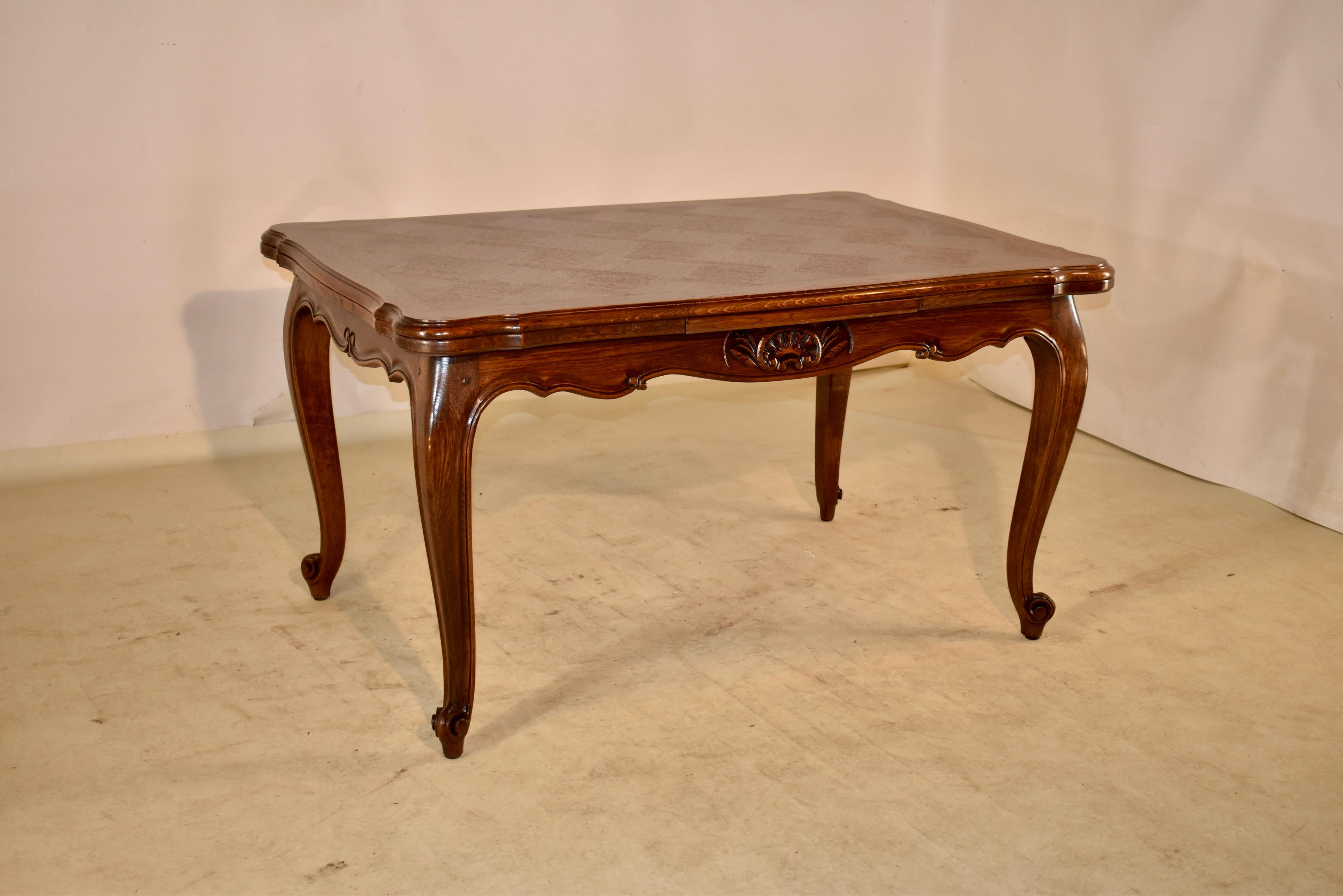 Circa 1910 French draw leaf table made from oak with a banded and parqueted top and two extending leaves, following down to a hand scalloped and carved decorated apron and supported on hand carved cabriole legs with carved shell decorations on the