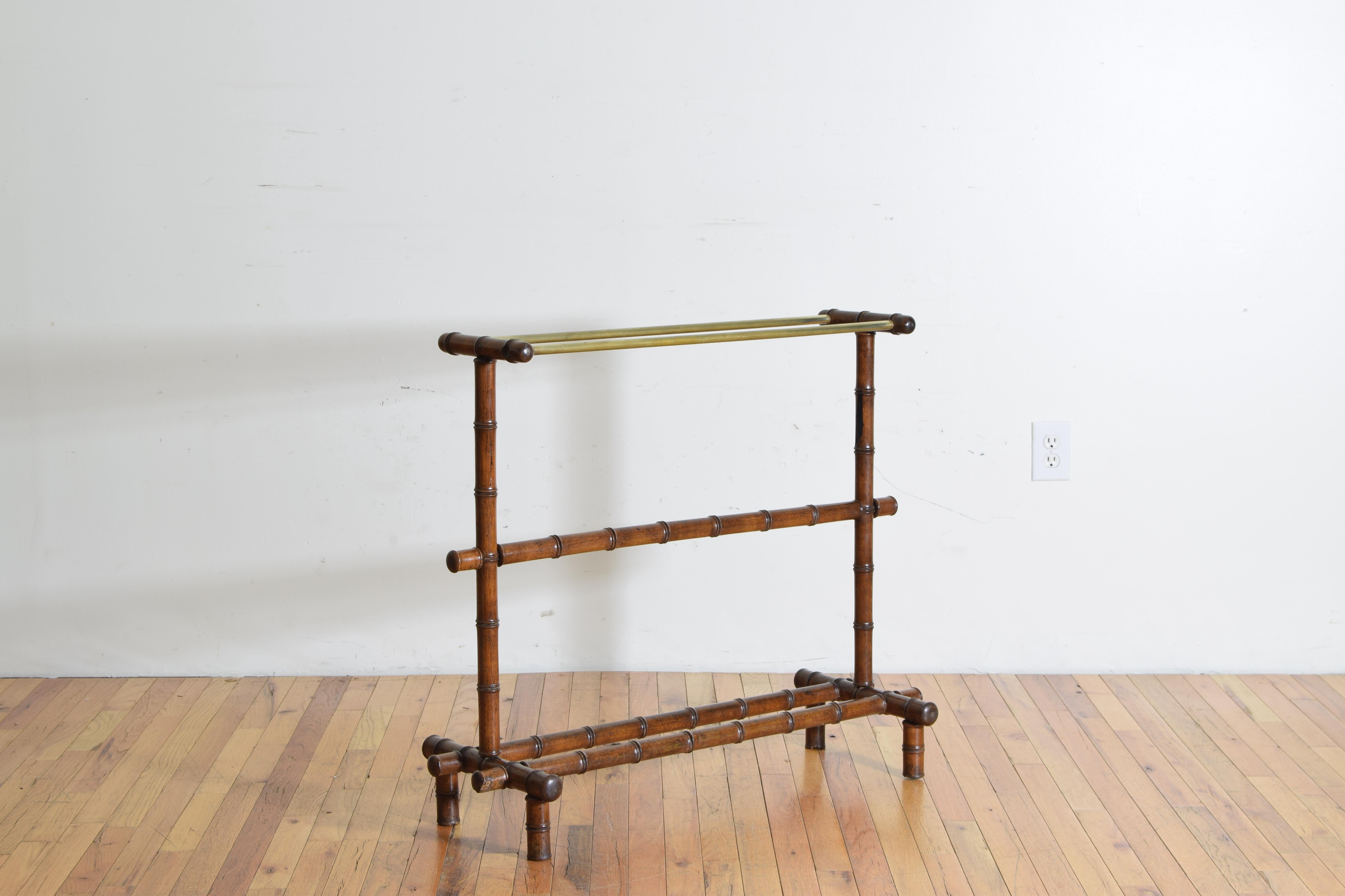 Raised on straight feet the trestle-form sides joined by a bottom double stretcher and a middle single stretcher, the upper portion with two brass hanging rods.
