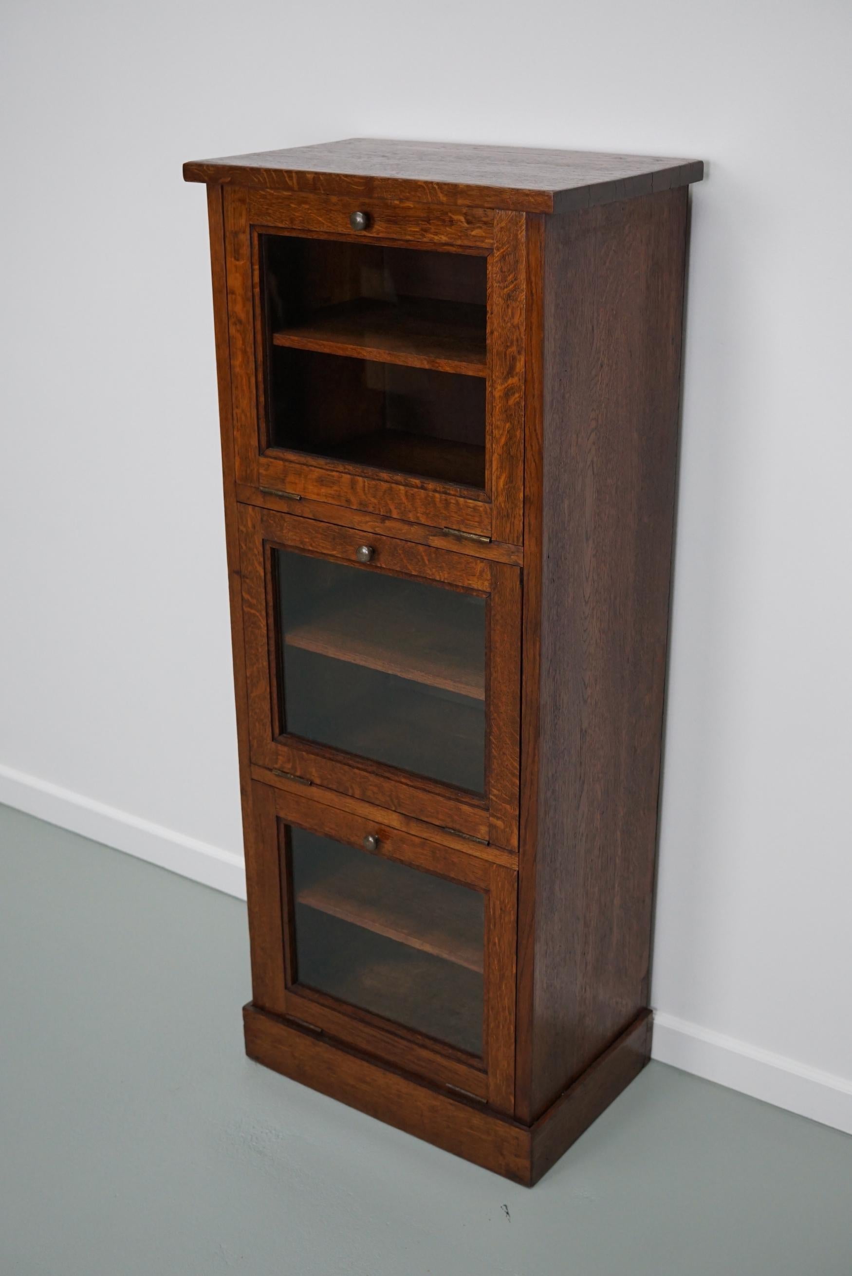 This haberdashery cabinet was produced during the 1930s in France. This piece features 3 folding doors in oak with glass fronts and brass knobs. It was originally used in a luxury warehouse in Paris. The interior dimensions of the 6 compartments