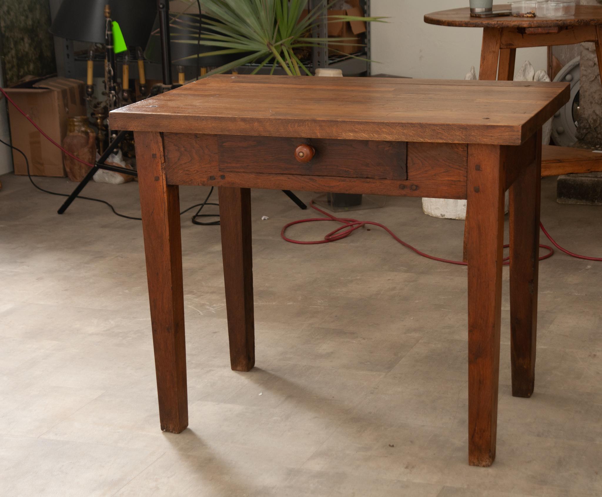 A French oak work table from the late 19th century, constructed with peg joinery and featuring a thick top, protruding corners, single drawer, and tapered legs. Created in Burgundy, France circa 1890 and used as a kitchen prep table, this piece has