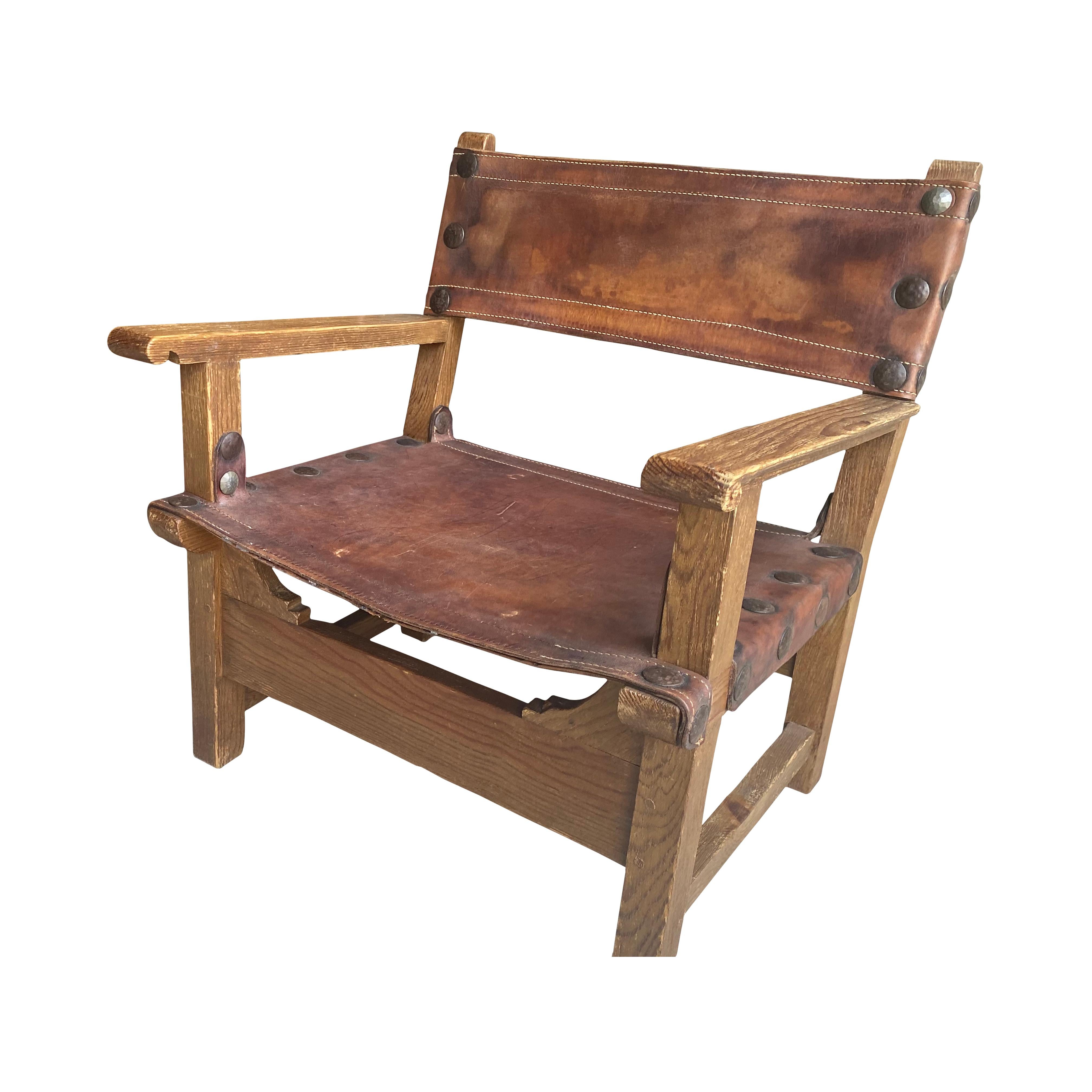 French oak and leather sling chair, typical of the chateau or chalet style from midcentury residences in the French Alps. Fantastic oversized nail heads and patina on leather add character. Two available, sold separately.