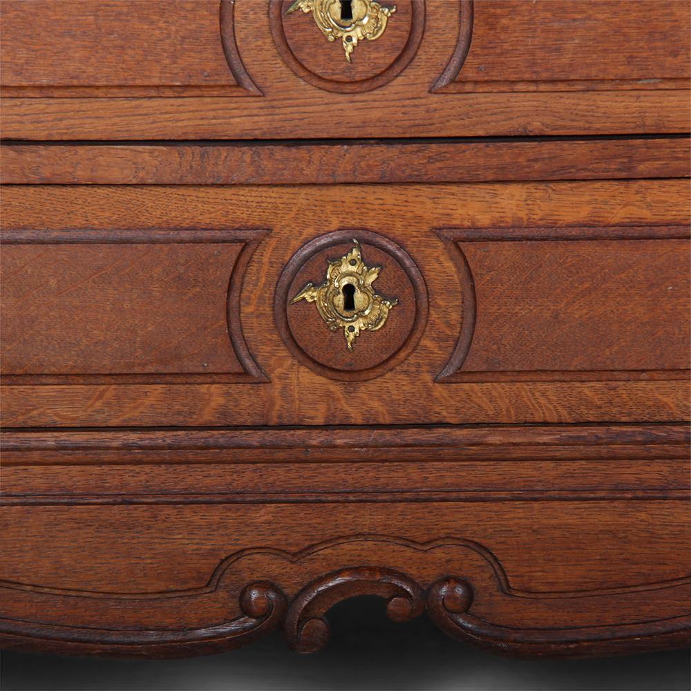 A late 19th century carved oak Louis XV style French commode with two short over three long drawers, all with their original gilt bronze pulls, the drawers further embellished with gilt escutcheons.
The pieces is raised on carved cabriole legs with