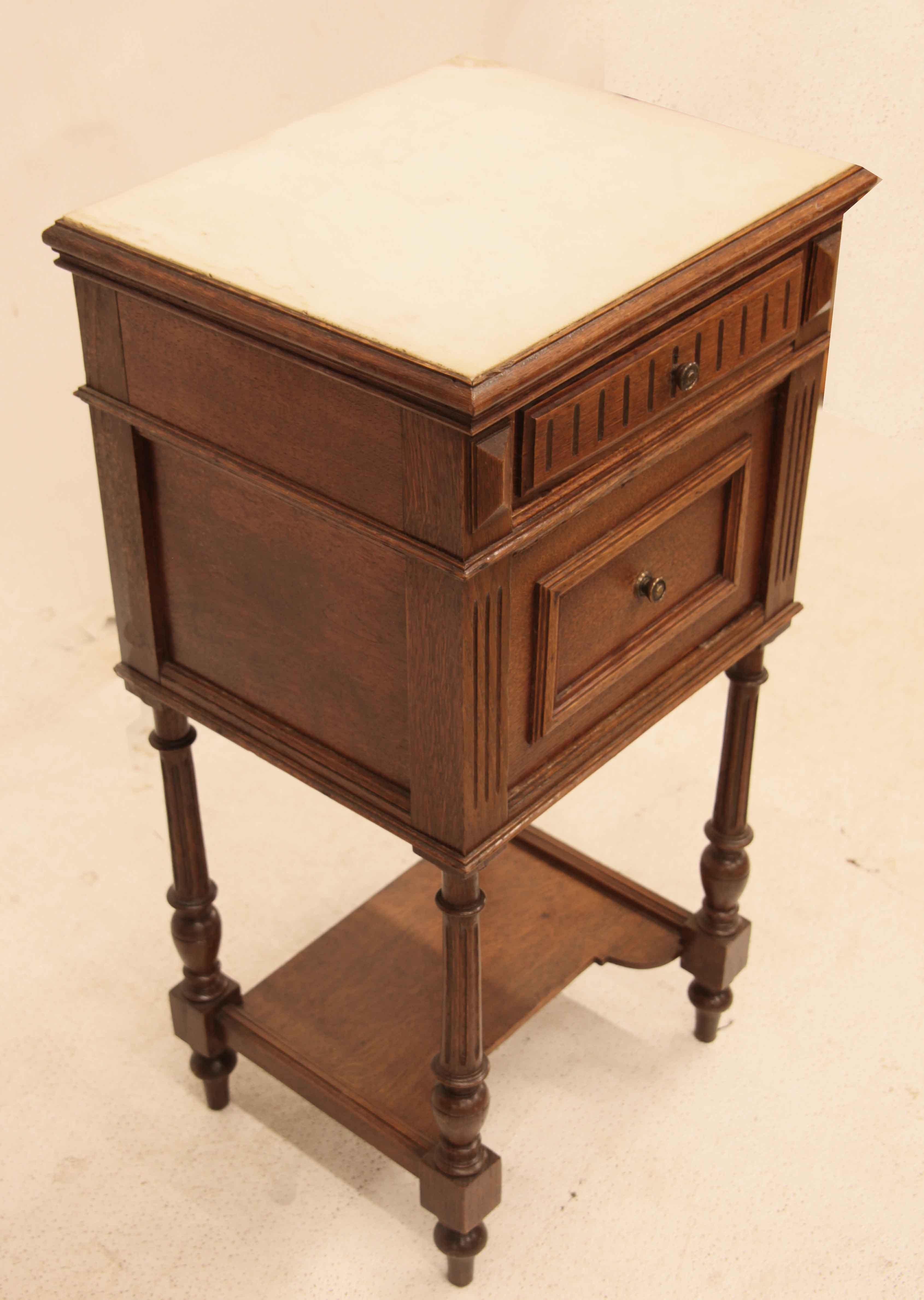 French oak marble top stand,  the white marble top has a single drawer below it, door below with open interior for storage.  The turned legs are fluted and taper with a lower shelf attached . 