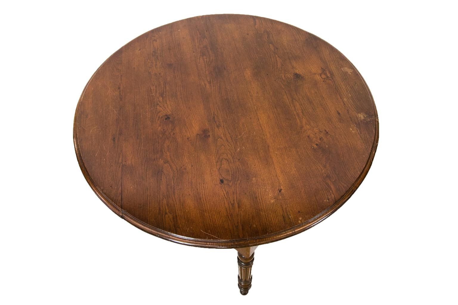 French oak round table has turned and reeded legs with exposed peg construction and a bull nosed molded top. There is one very long, deep drawer.