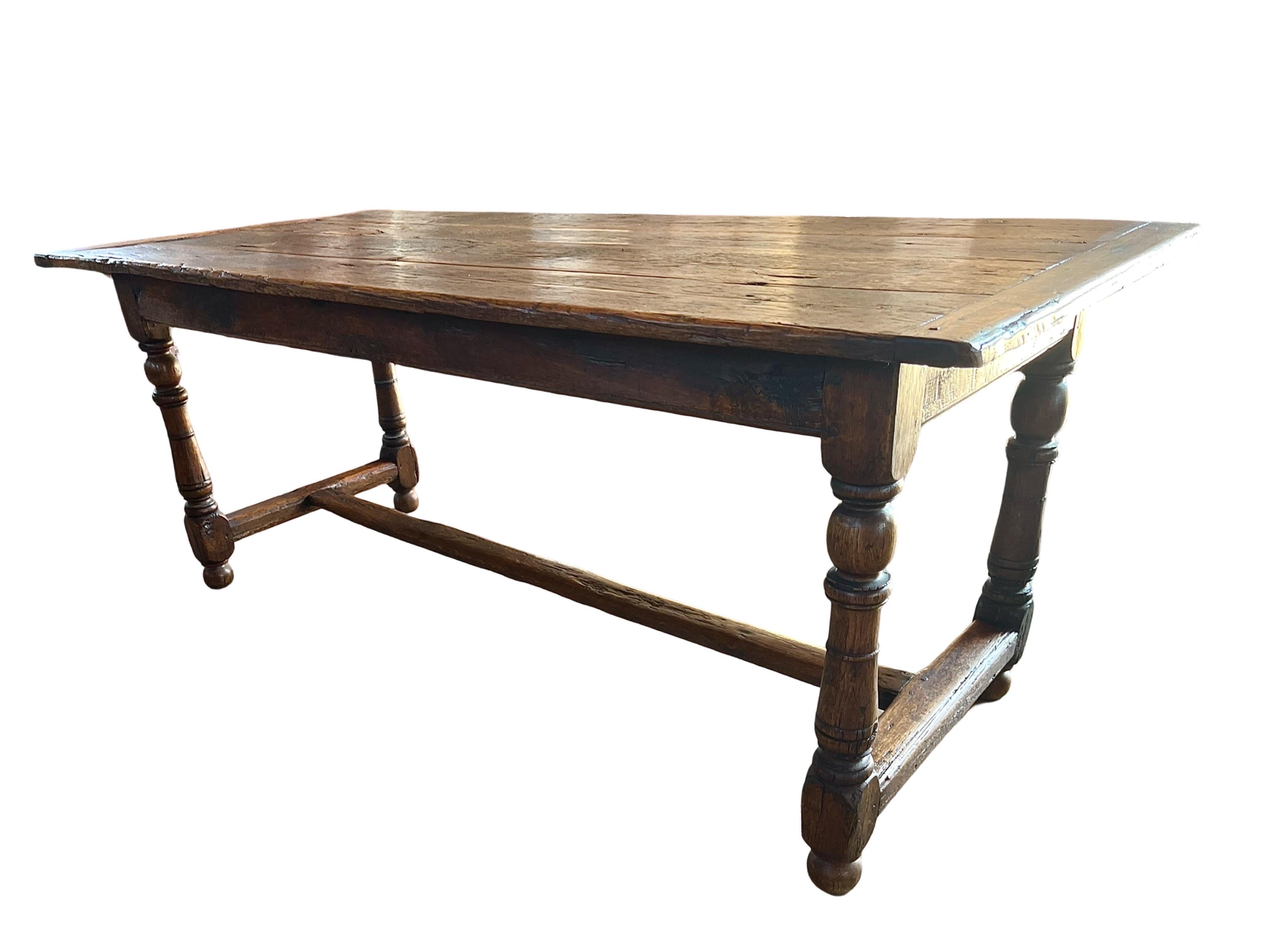 Tavolo da pranzo/cucina realizzato a mano in Francia all'inizio del 1800 con legno di Oak e struttura a pioli. Il piano presenta quattro lunghe tavole inchiodate al grembiule e incastrate in due tavole di pane a ciascuna estremità. I bordi sono