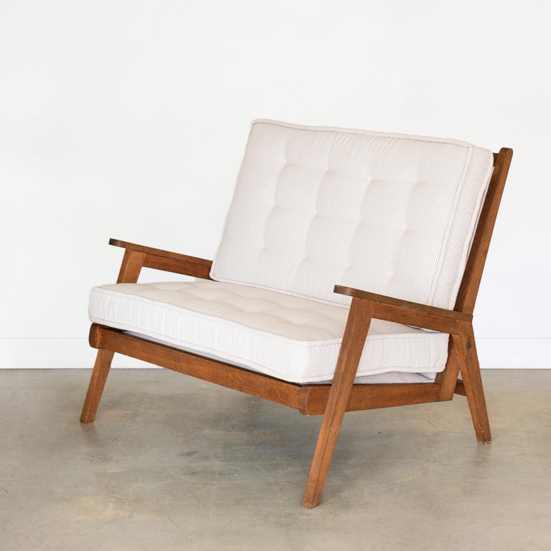 Beautiful oak wood settee from France, 1950s. Original light wood frame with angled arms and legs. Newly upholstered seat cushions in a taupe and white ticking stripe. 