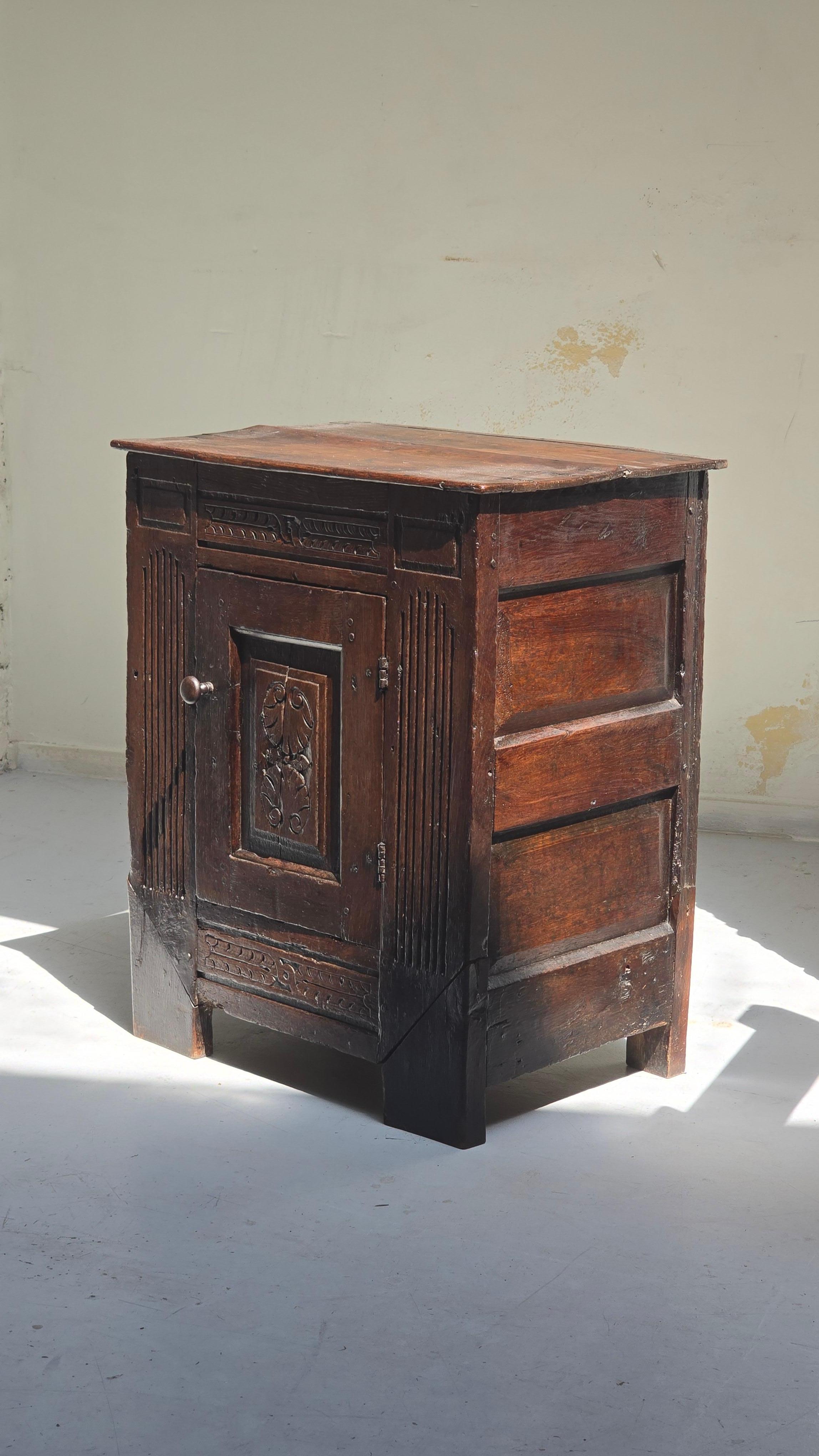 Charmanter kleiner Beistellschrank aus massiver Eiche mit geschnitzten Elementen aus dem 18. Jahrhundert.
Wahrscheinlich im 19. Jahrhundert zusammengebaut oder restauriert, weist das Stück eine reiche Patina, vertikale kannelierte Paneele und