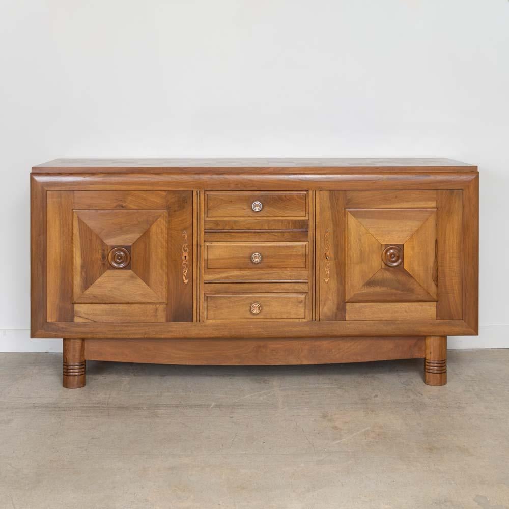 Incredible oak sideboard in the style of Charles Dudouyt from France, 1940s. Beautiful carved wood detail on cabinet doors and legs. Two doors, each with a middle shelf and three drawers in the center. Original metal hardware with bronze patina.