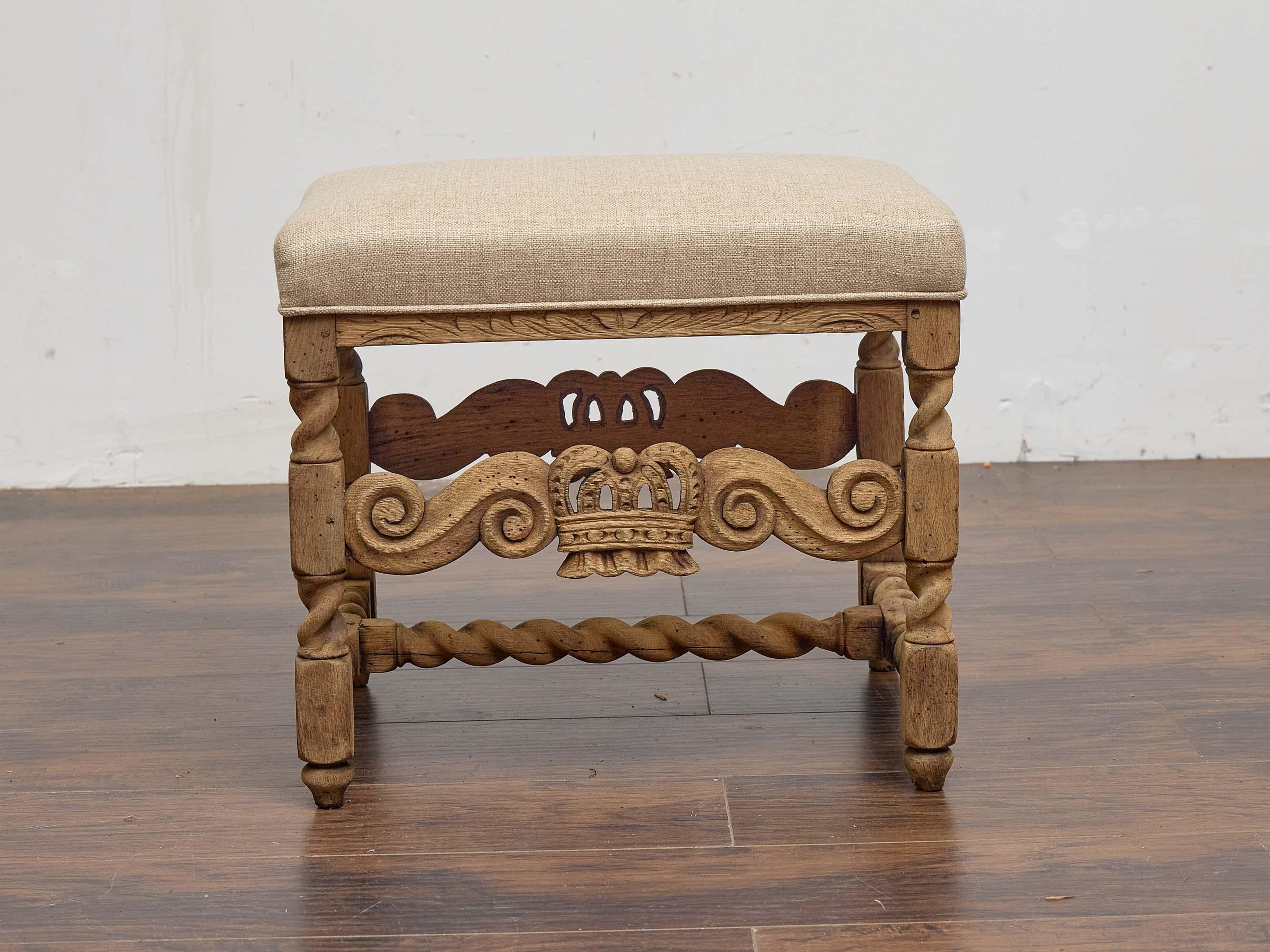 This richly detailed 19th-century French stool is carved from bleached oak and features an ornate apron centered with a regal crown motif framed by symmetrical scrollwork. The stool’s expressive silhouette is further enhanced by boldly turned legs