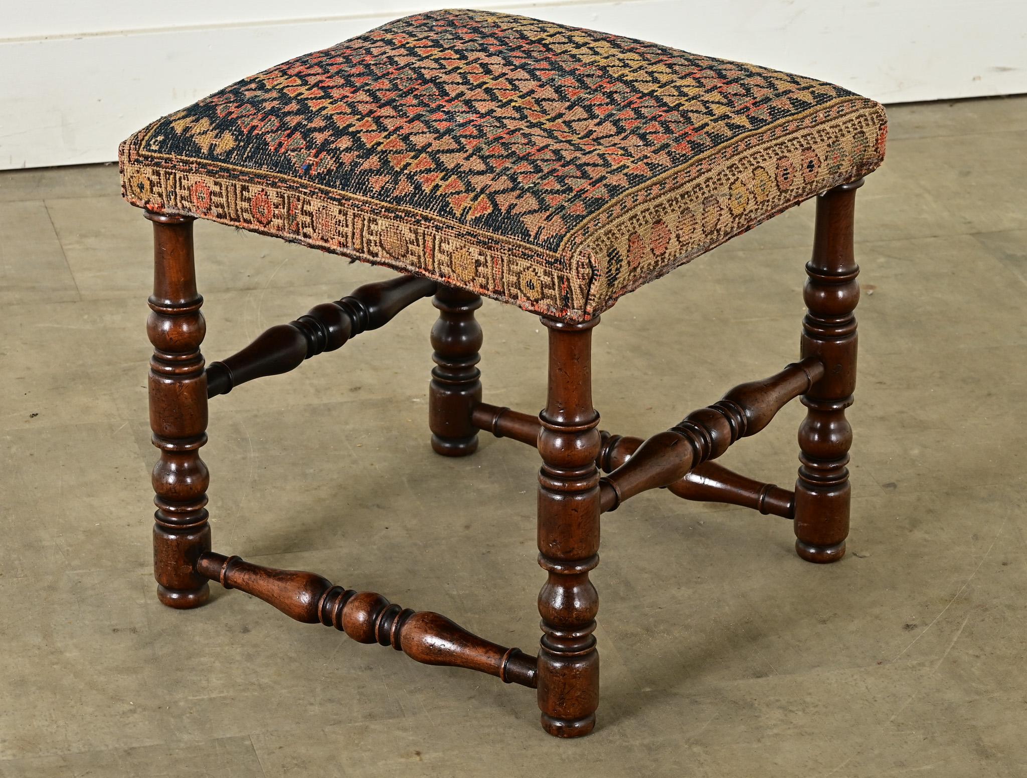 A French oak and tapestry stool made in the 1800’s. The seat is upholstered in a woven material of geometric patterning, in colors of deep indigo and shades of red among the undyed yarns. Raised on turned, solid oak legs and stretched on each side