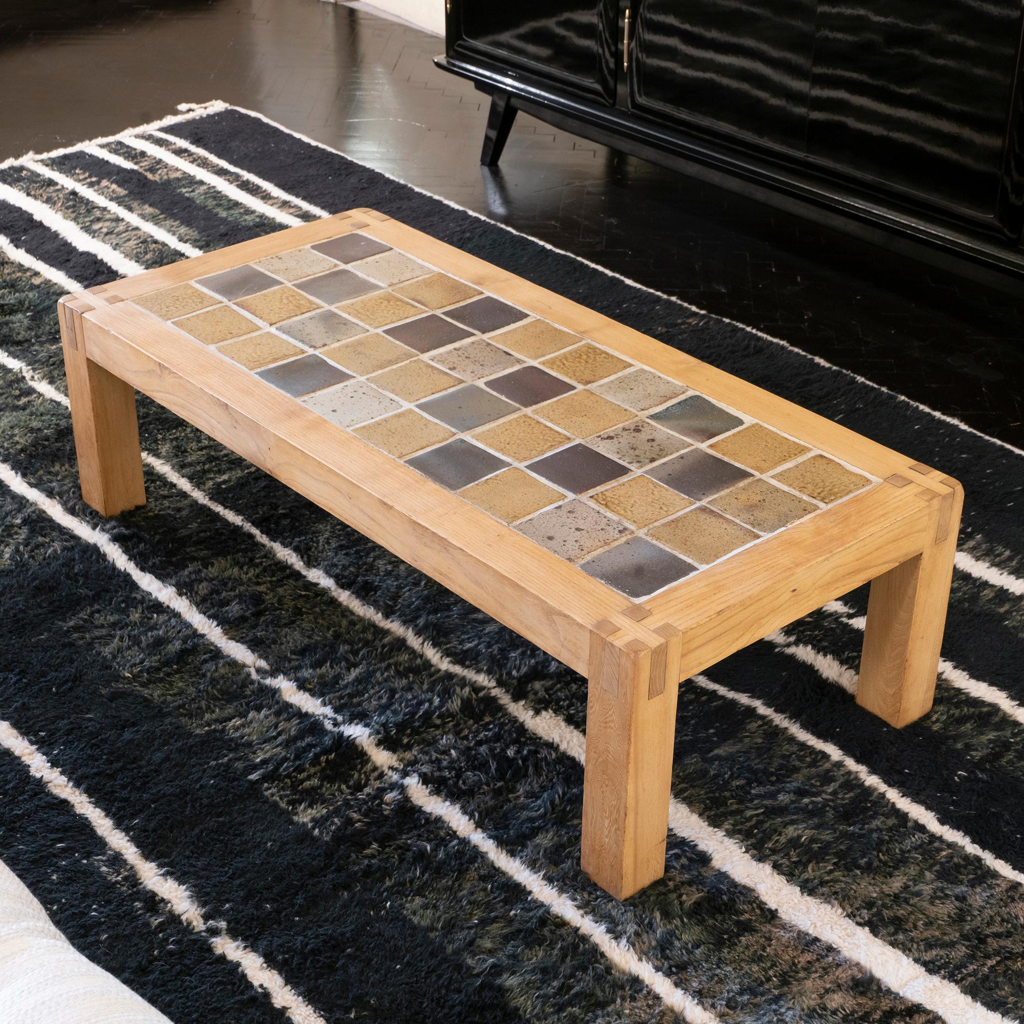 French ceramic coffee table is typical 1960s, with its solid oak wood base and shades of cream/grey/yellow and brown ceramic tales, restored and in a great vintage condition.
 