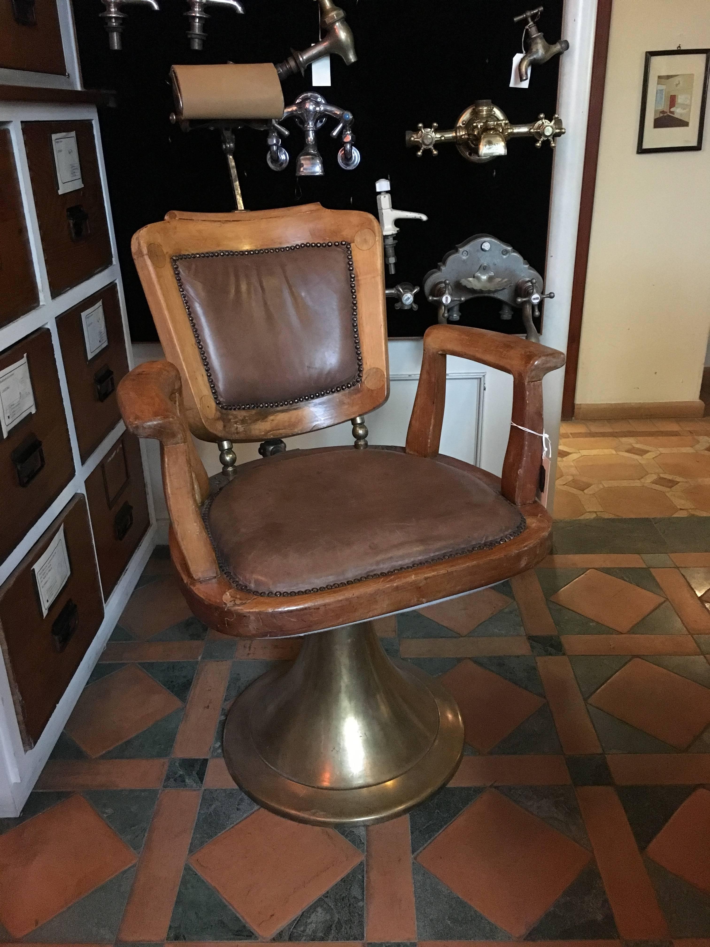 French oakwood and leather barber chair with brass base from 1940s.