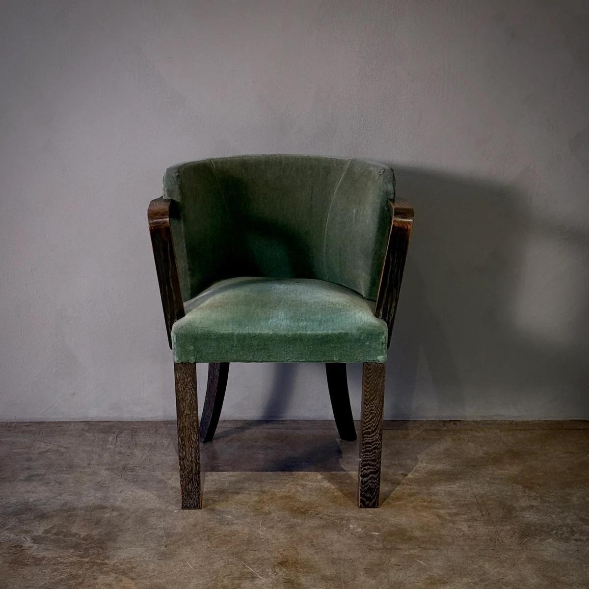 Questa poltrona da ufficio vintage, rivestita in morbido velluto verde, emana un fascino di metà secolo grazie ai braccioli in legno e allo schienale curvo. Il design compatto e la palette di colori delicati rendono la sedia un'aggiunta sobria ma