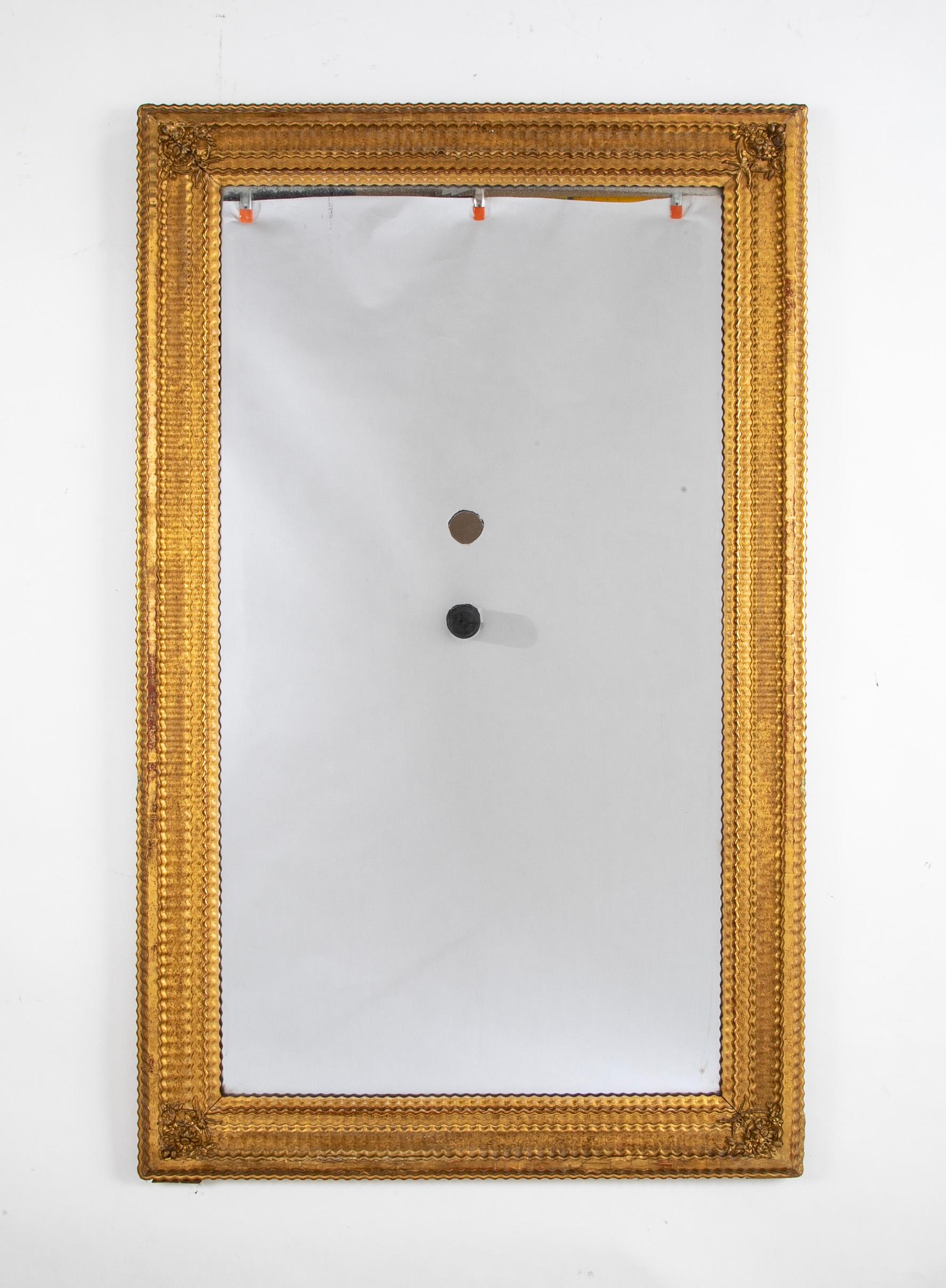 Miroir français en verre ancien avec cadre en bois doré et tabliers feuillagés dans les angles. 