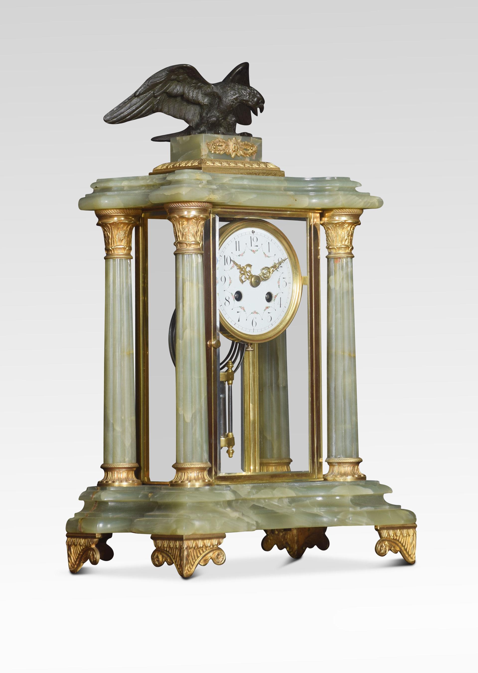 Late 19th century French onyx clock set, the case surmounted with a cast bronze eagle upon a rectangular plinth, supported on four fluted Corinthian columns applied with gilt metal mounts, encasing the four glass panels encasing the enameled dial