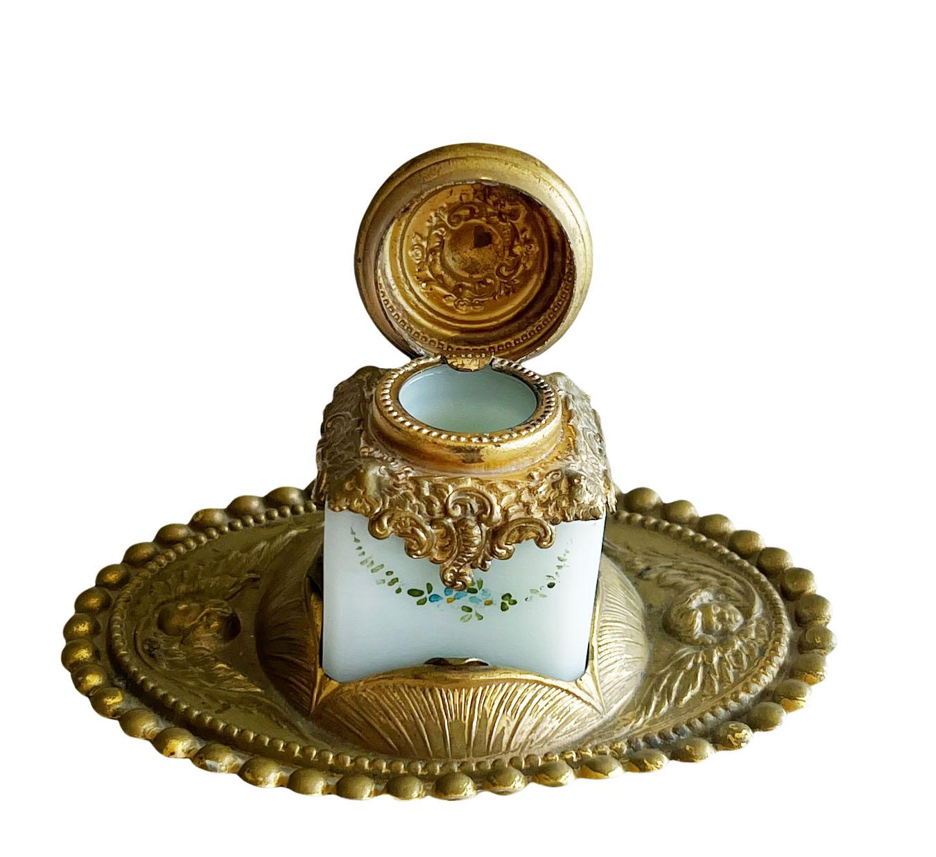 A beautiful pale blue opaline inkwell with small hand painted flowers. With an antique brass top and incased into the brass base. The base has angle heads on either side of the ink bottle. The inkwell appears to have never been used.