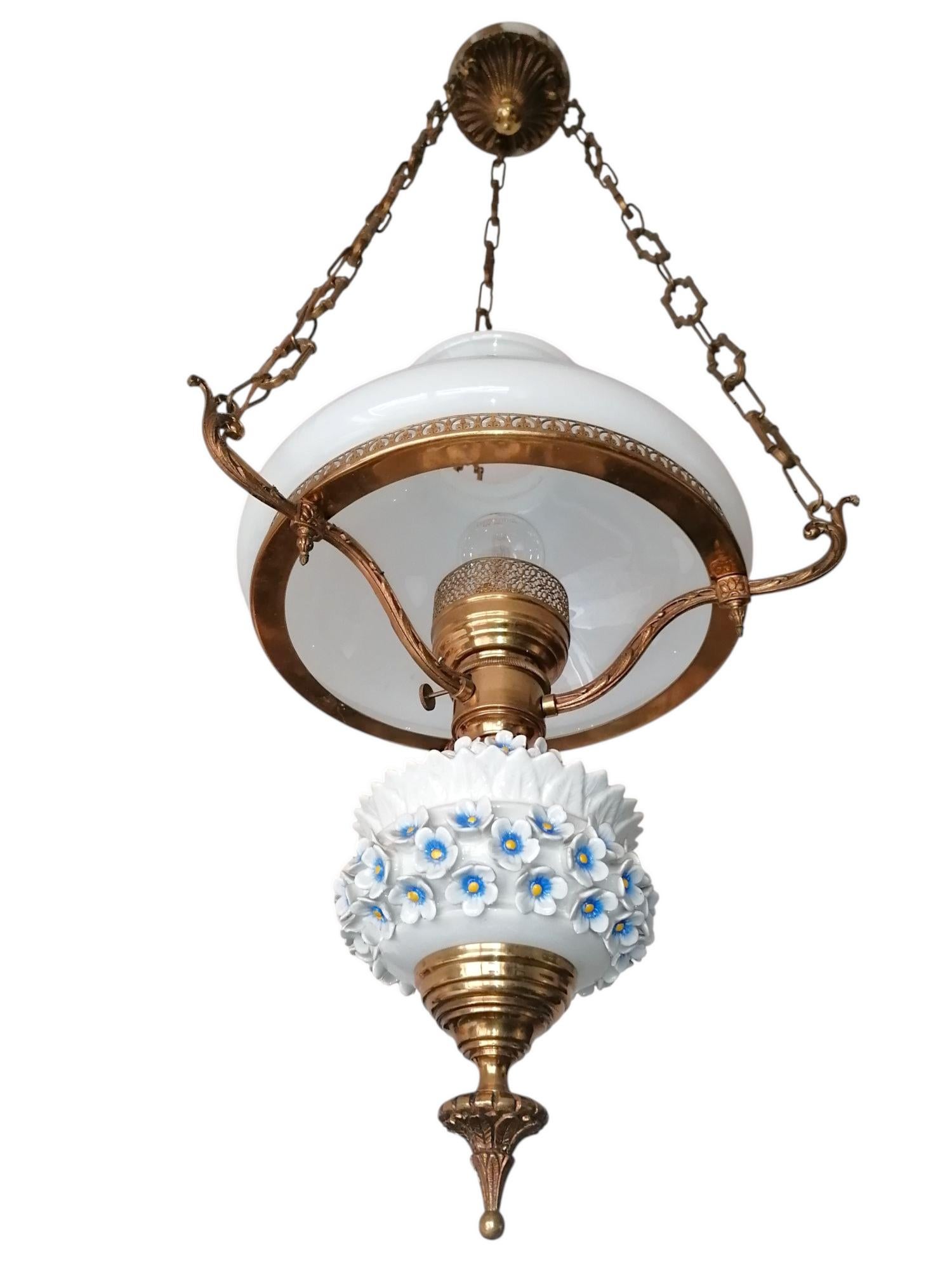 Magnifica lampada a olio francese a sospensione. Questo raro pezzo combina magistralmente il vetro opalino bianco con una struttura in bronzo dorato. Il corpo centrale è ornato da delicati fiori di porcellana applicati a mano in bianco con i centri